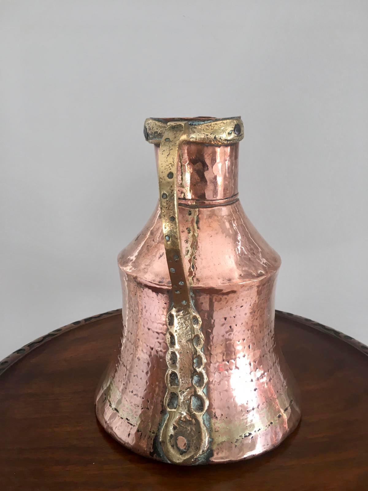 An unusual antique Arts & Crafts copper and brass milk jug having an attractive unusual shaped handle and beautifully designed and handcrafted body with a band of brass expertly moulded into the copper, making this a marvelous decorative piece.
  