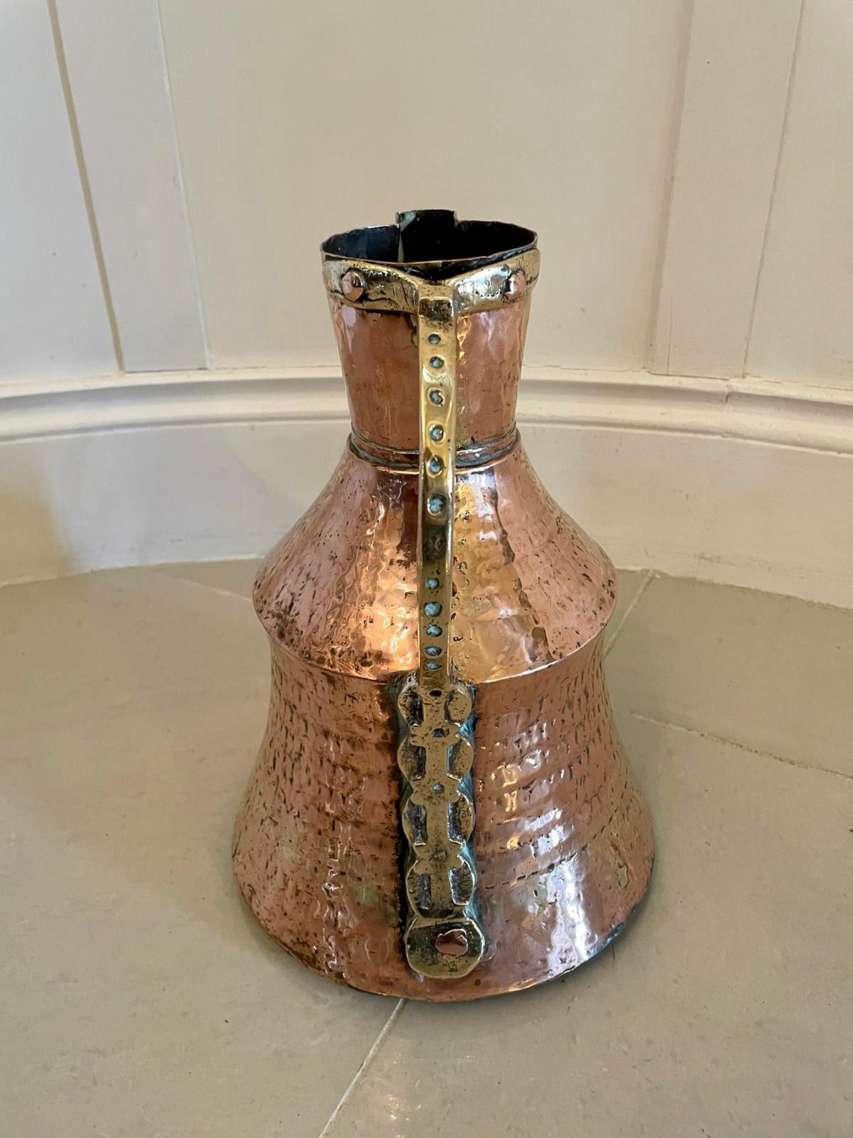 Large antique Arts & Crafts copper and brass milk jug

An unusual large antique Arts & Crafts copper and brass milk jug having an attractive unusual shaped handle and beautifully designed and handcrafted body with a band of brass expertly moulded