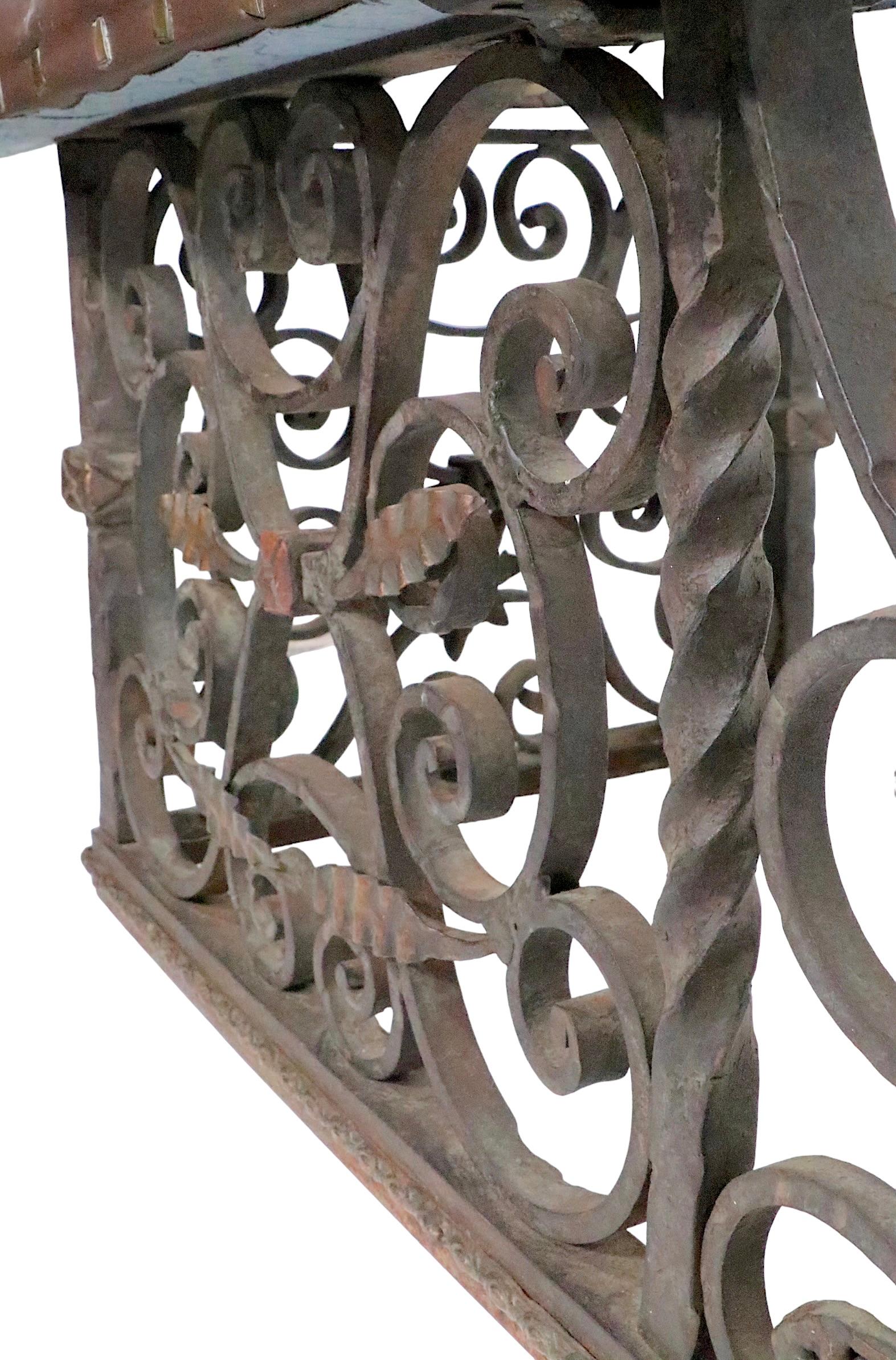 Exceptional wrought iron club, or bench, fender having ornate metal work and an upholstered bench seat ( later, but not new vinyl upholstery ). This impressive piece shows Spanish, Moorish, Gothic and Arts and Crafts influences. The quality of the