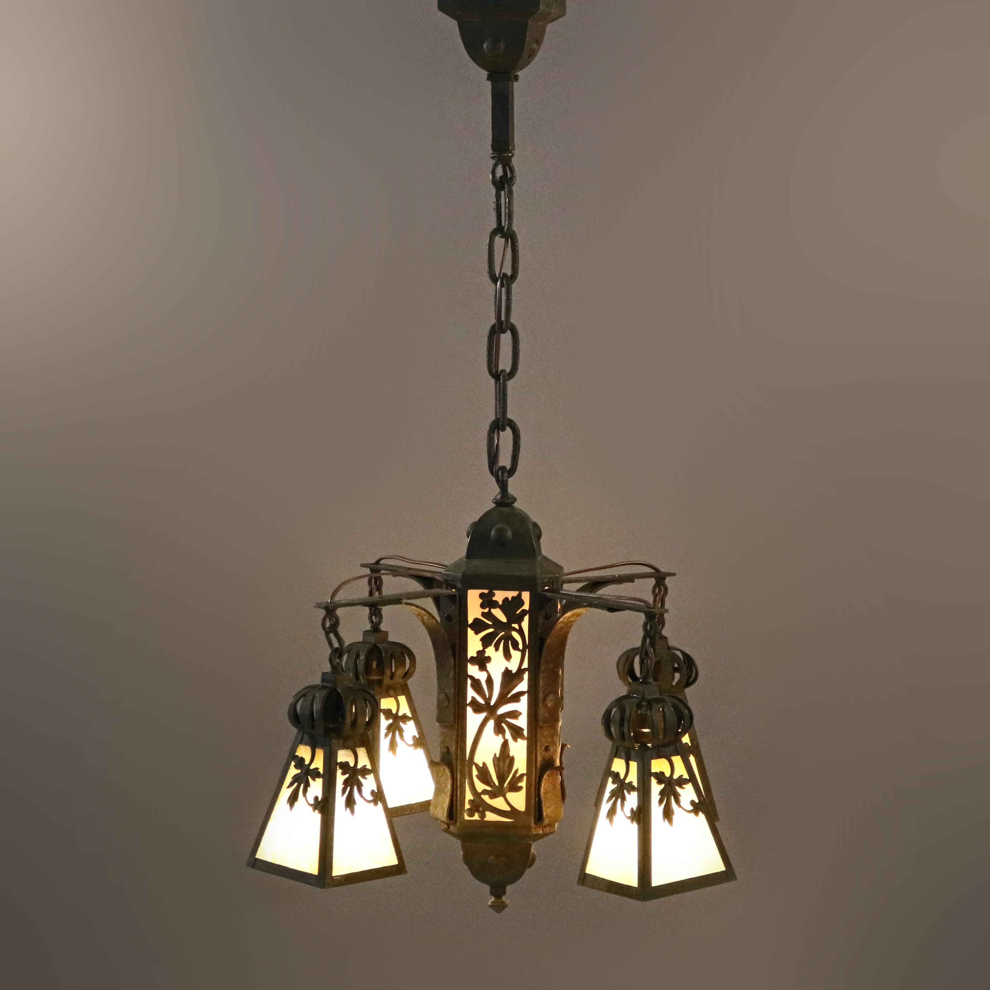 An antique Arts & Crafts chandelier offers central light with four flared drop lights each having hammered metal frames with cut-out foliate design and housing slag glass panels, c1920

Measures - 37.25'' H x 21'' W x 21.25'' D.

Catalogue Note: Ask