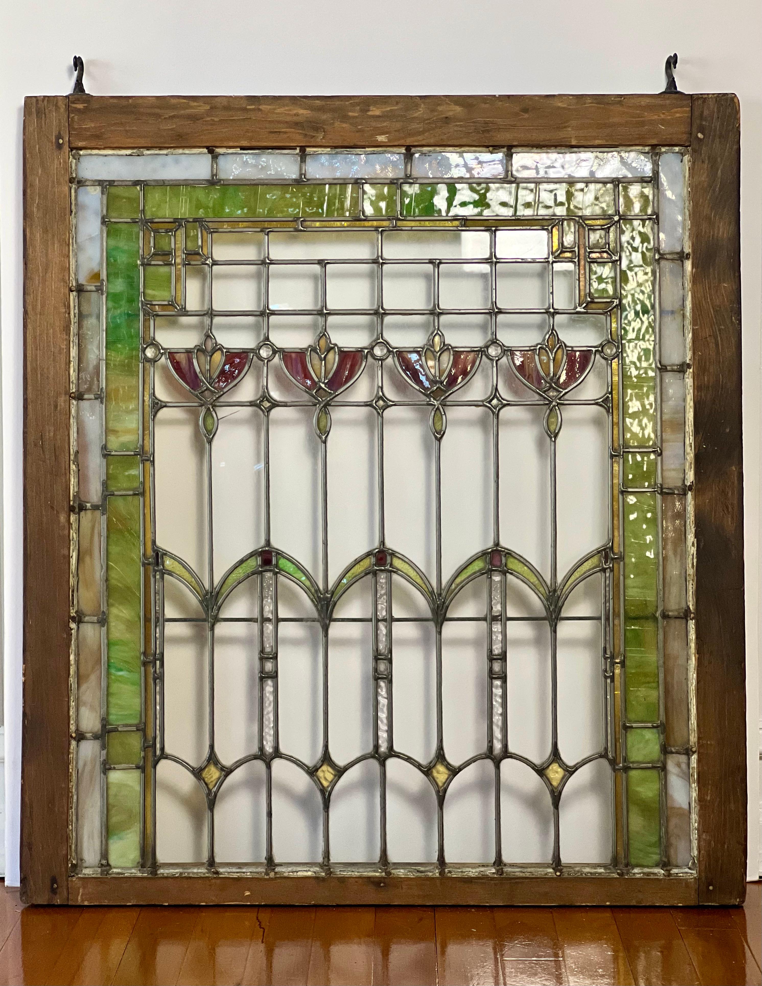 Arts and Crafts leaded stained and clear glass window with floral theme in wood frame, c. 1890-1910.

Balance and beauty come together in soft shades of green, ruby, blush, pale blue and hints of gold to form this stunning floral design. Geometric