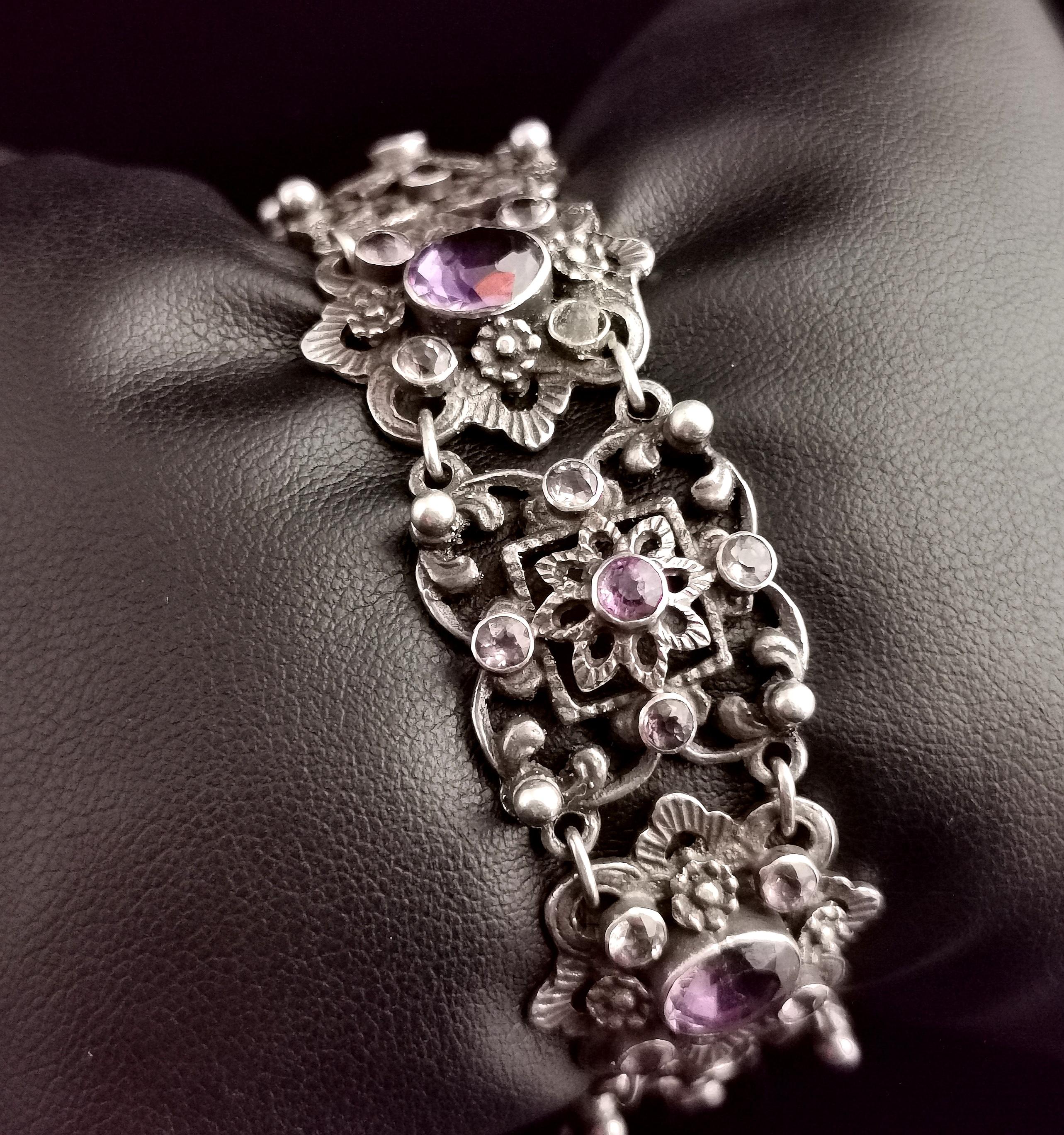 A beautiful antique Arts and Crafts design sterling silver and Amethyst bracelet.

This is a very pretty and well designed bracelet with elaborate floral design links which are joined together in an alternating pattern.

One type of link is set with