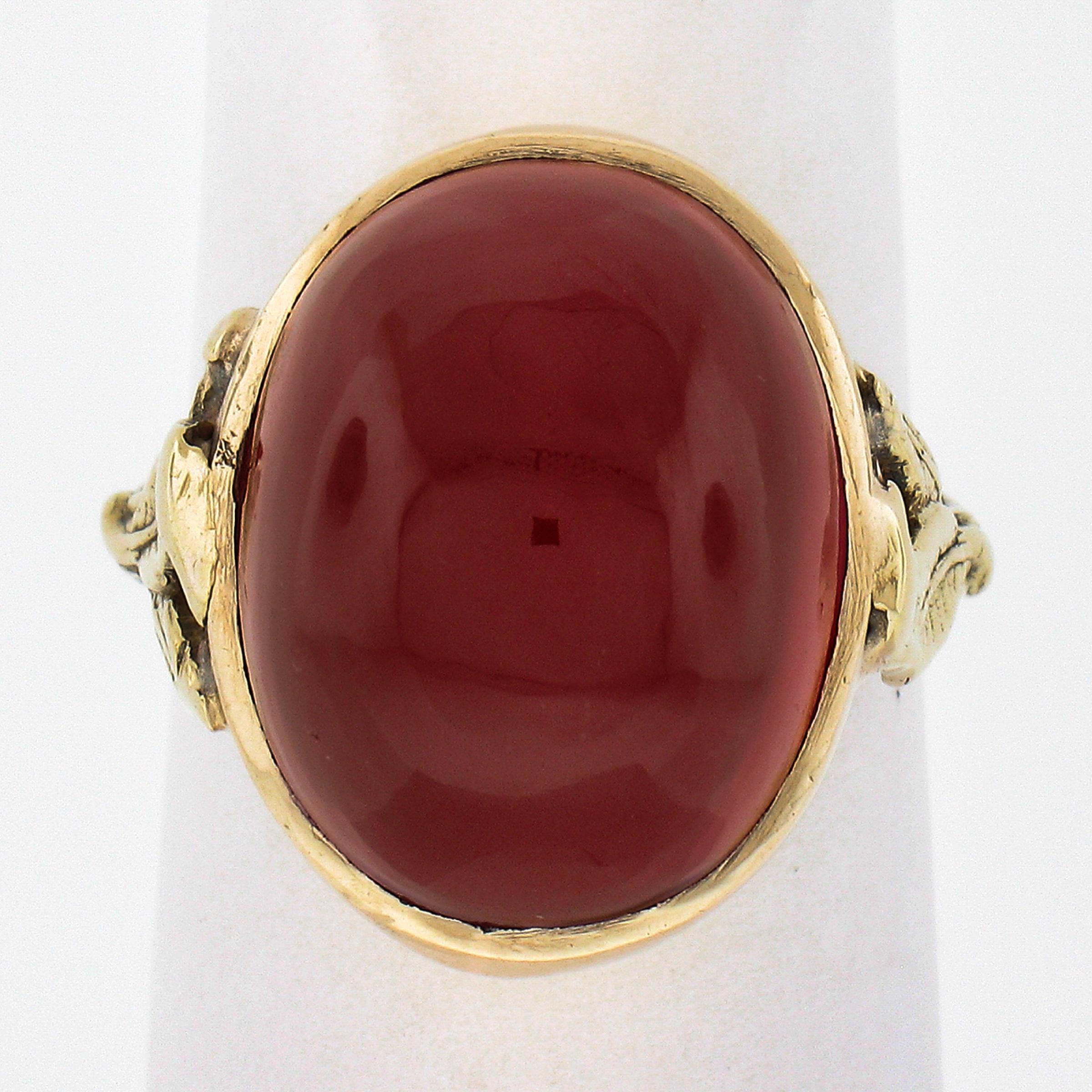 Here we have a beautiful antique solitaire ring crafted from solid 14k yellow gold during the Arts & Crafts movement and features a large, oval cabochon cut, red stone neatly bezel set at the center. This stone stands out with its super attractive