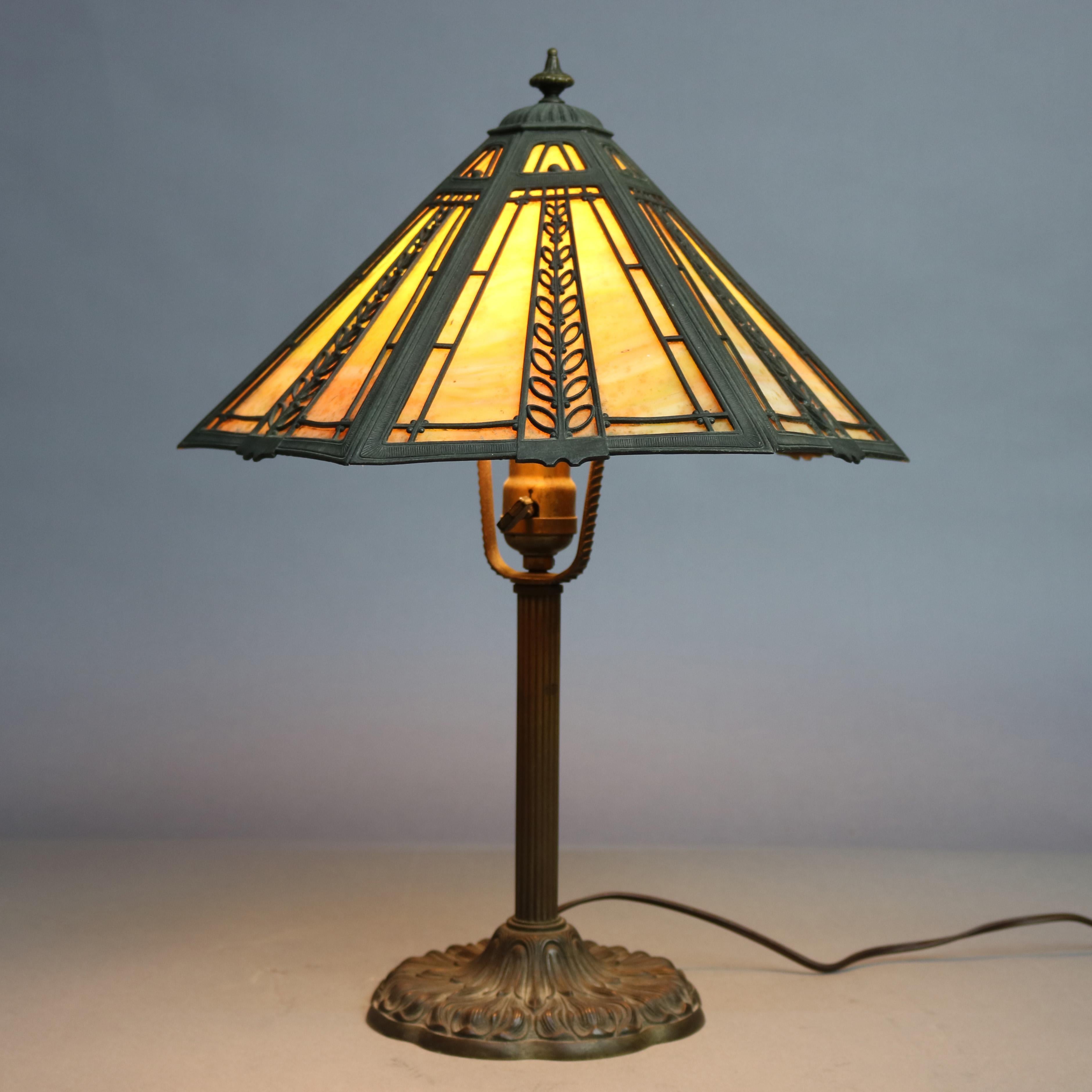 An antique table lamp by Miller offers paneled slag glass shade with foliate filigree frame surmounting single socket base having reeded column and foliate bas, circa 1920.

Measures- 19.5