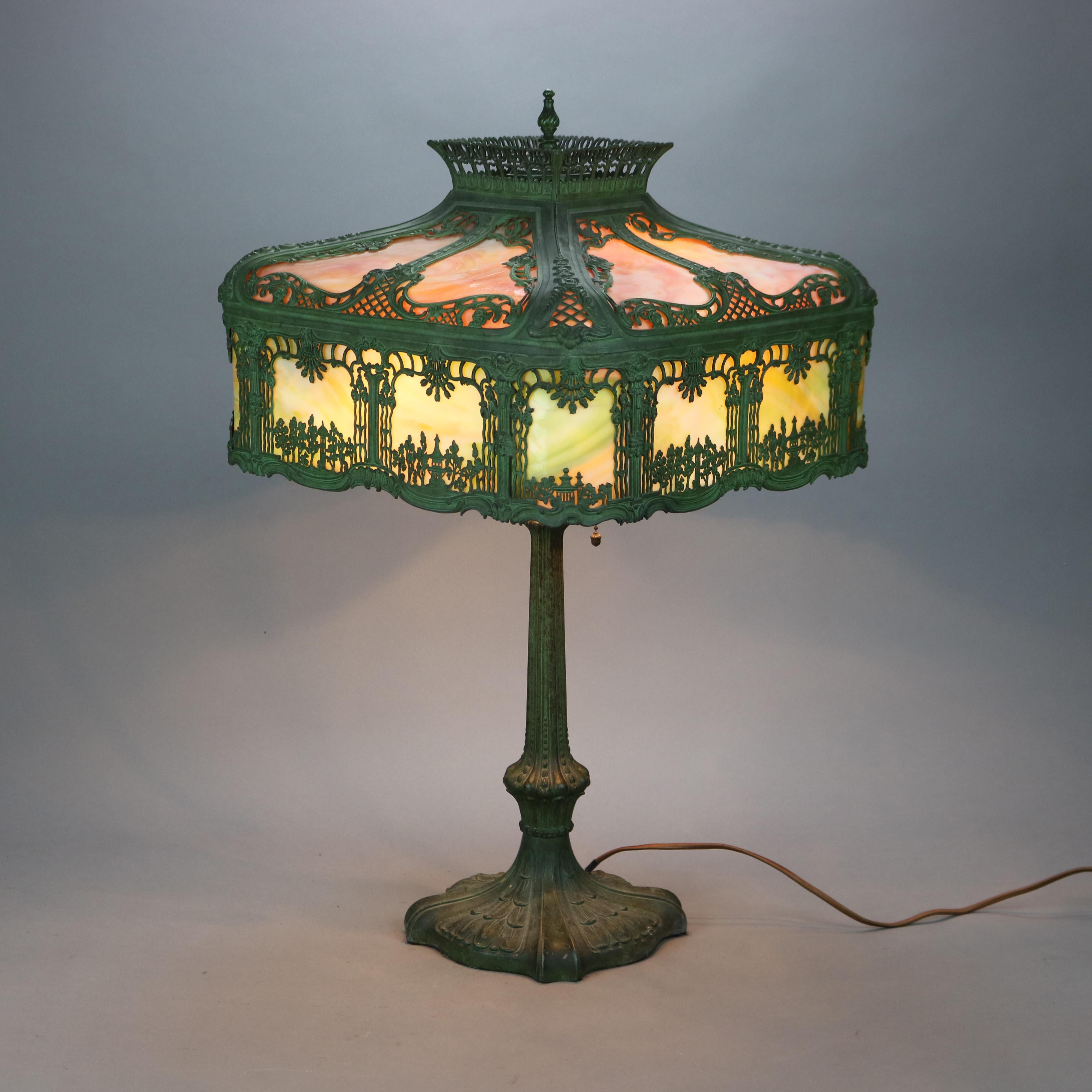 An antique Arts & Crafts table lamp in manner of Bradley and Hubbard offers pagoda style cast filigree shade with landscape scene having pagodas over cast triple socket base, c1920

Measures - 27.5'' H x 16'' W x 16'' D.