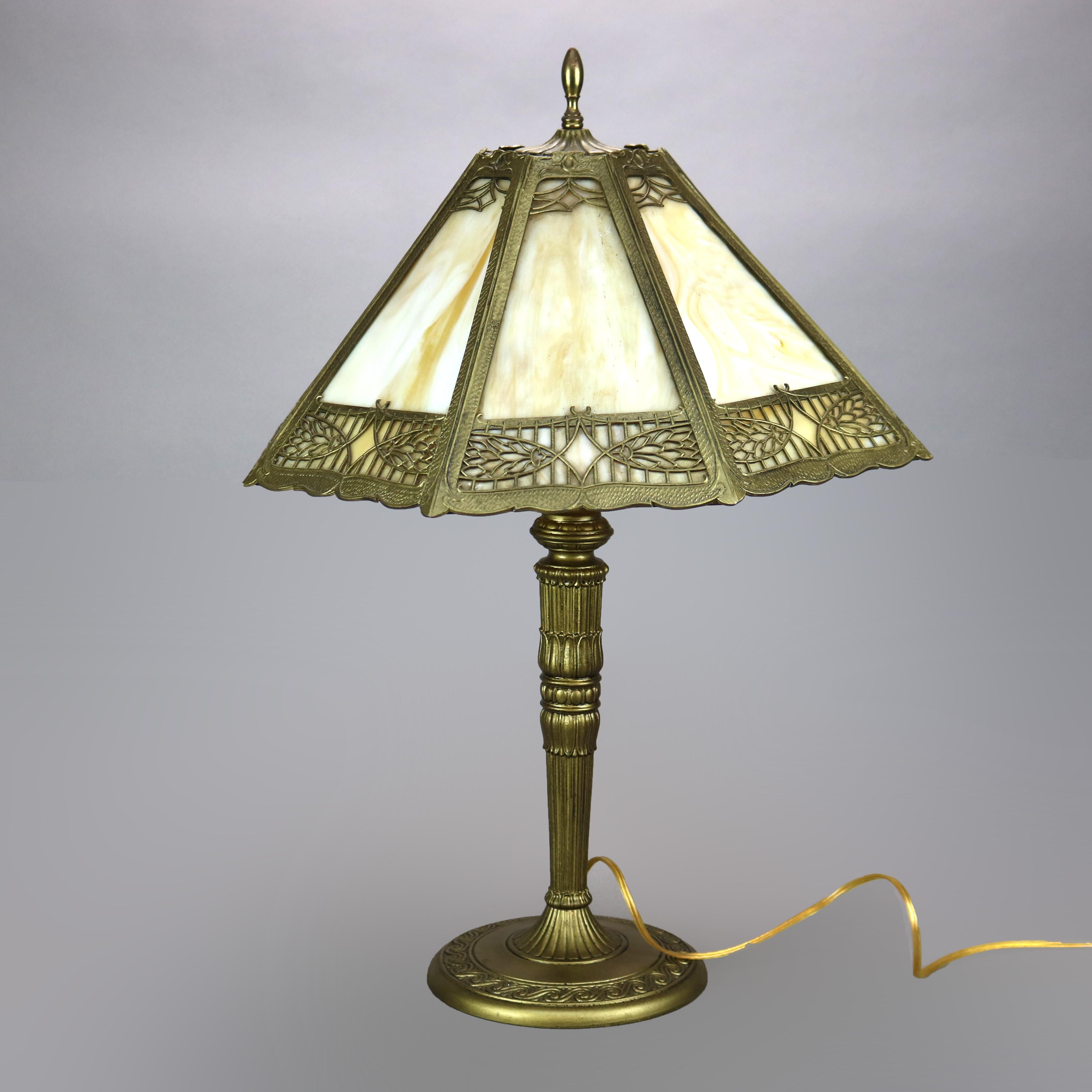 An antique Arts & Crafts table lamp in the manner of Bradley and Hubbard offer stylized foliate filigree frame housing slag glass panels over cast single socket base with foliate and wave embossed design, c1920 

Measures - 24.5'' H x 16.75'' W x
