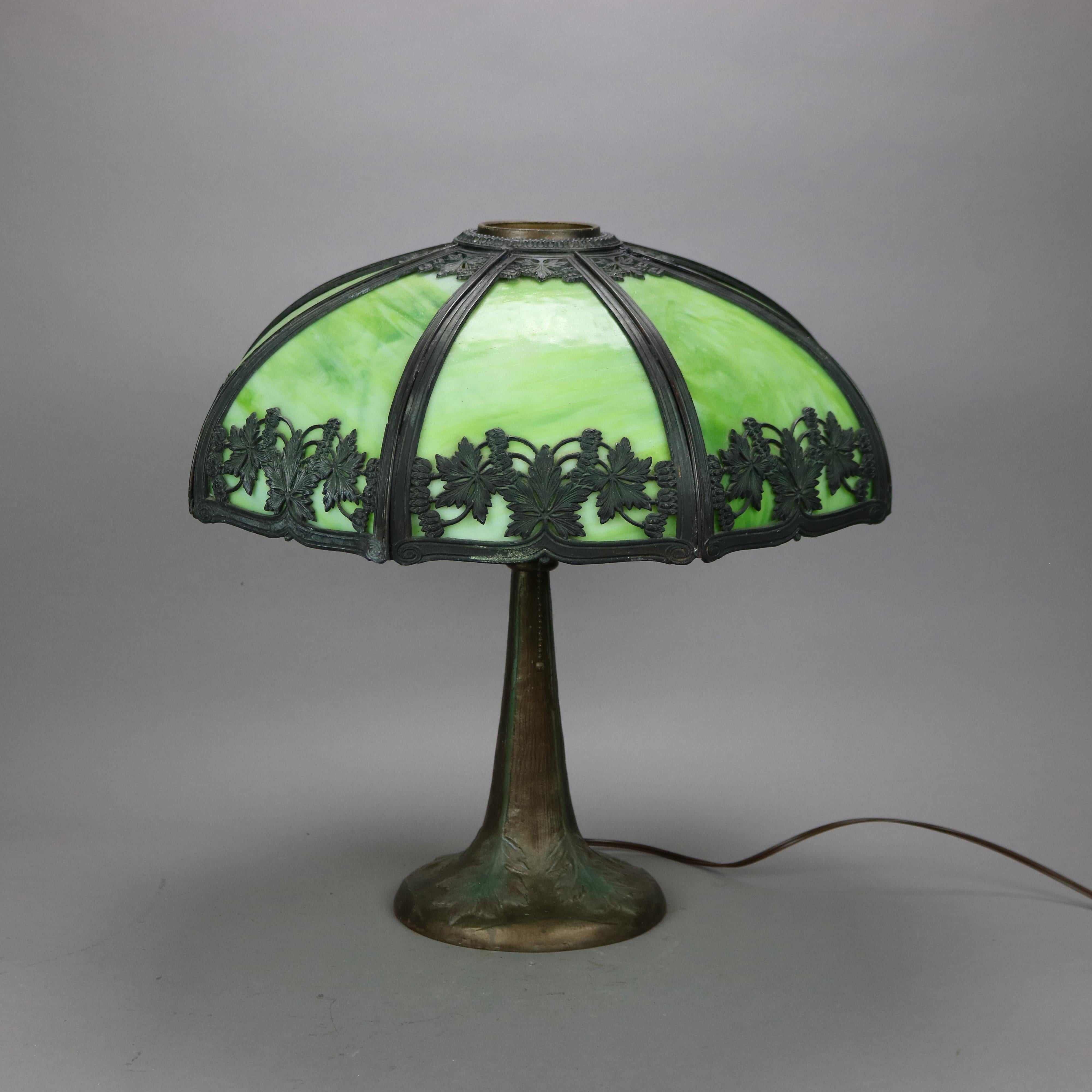 An antique Arts & Crafts table lamp in the manner of Bradley and Hubbard offers filigree cast shade with a leaf and vine pattern over double socket cast base having foliate elements in relief, c1920

Measures - 19'' H x 20.25'' W x 20.25'' D.