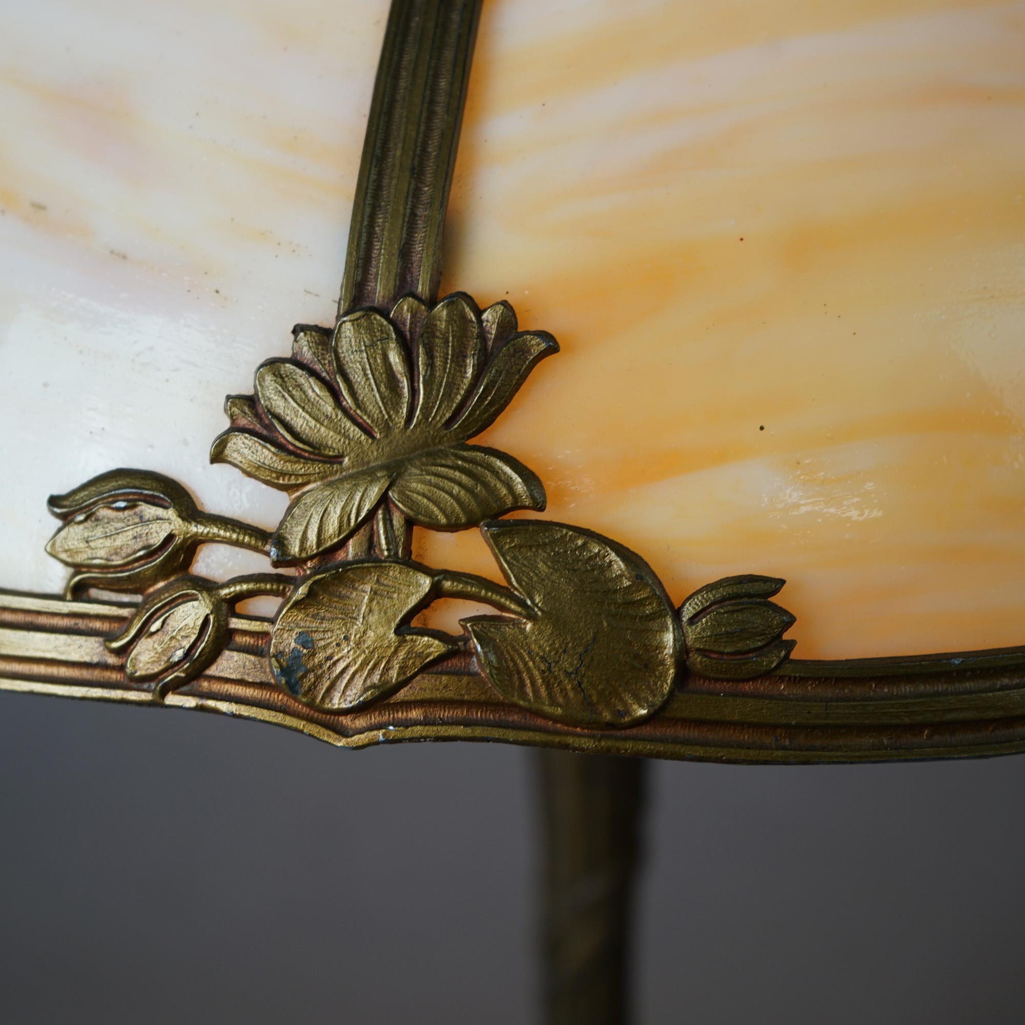 An antique Arts and Crafts table lamp in the manner of Bradley & Hubbard offers dome form shade with cast frame having lotus flower (or water lily) elements and housing bent slag glass panels over single socket base, c1920

Mesures - 21,5 