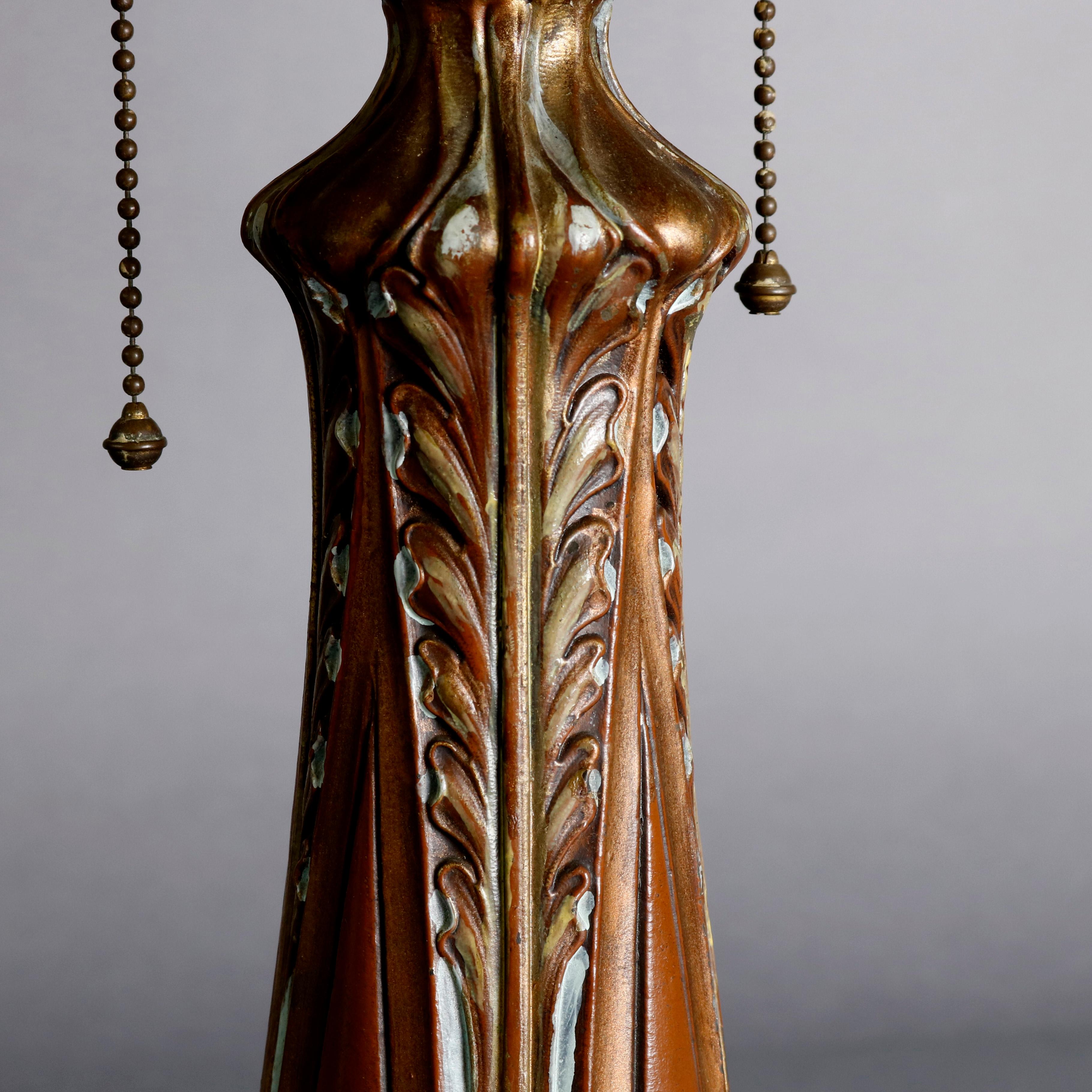 An antique Arts & Crafts Bradley and Hubbard School table lamp offers stylized foliate cast base with two sockets surmounted by six panel bent slag glass shade with cast frame having pierced design reminiscent of art deco, circa 1920

Measures: