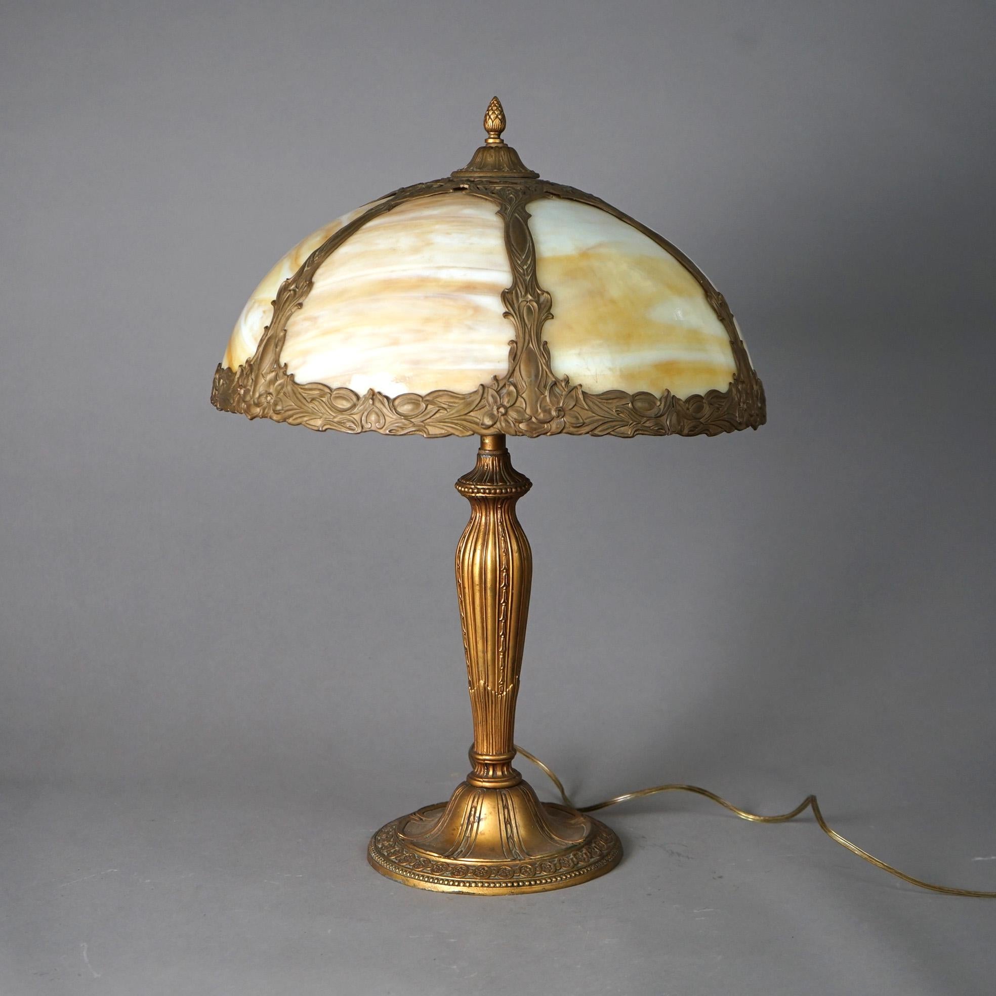 An antique Arts and Crafts table lamp by Bradley and Hubbard offers foliate cast dome form shade housing bent slag glass panels over double socket base, c1920

Measures - 22.5