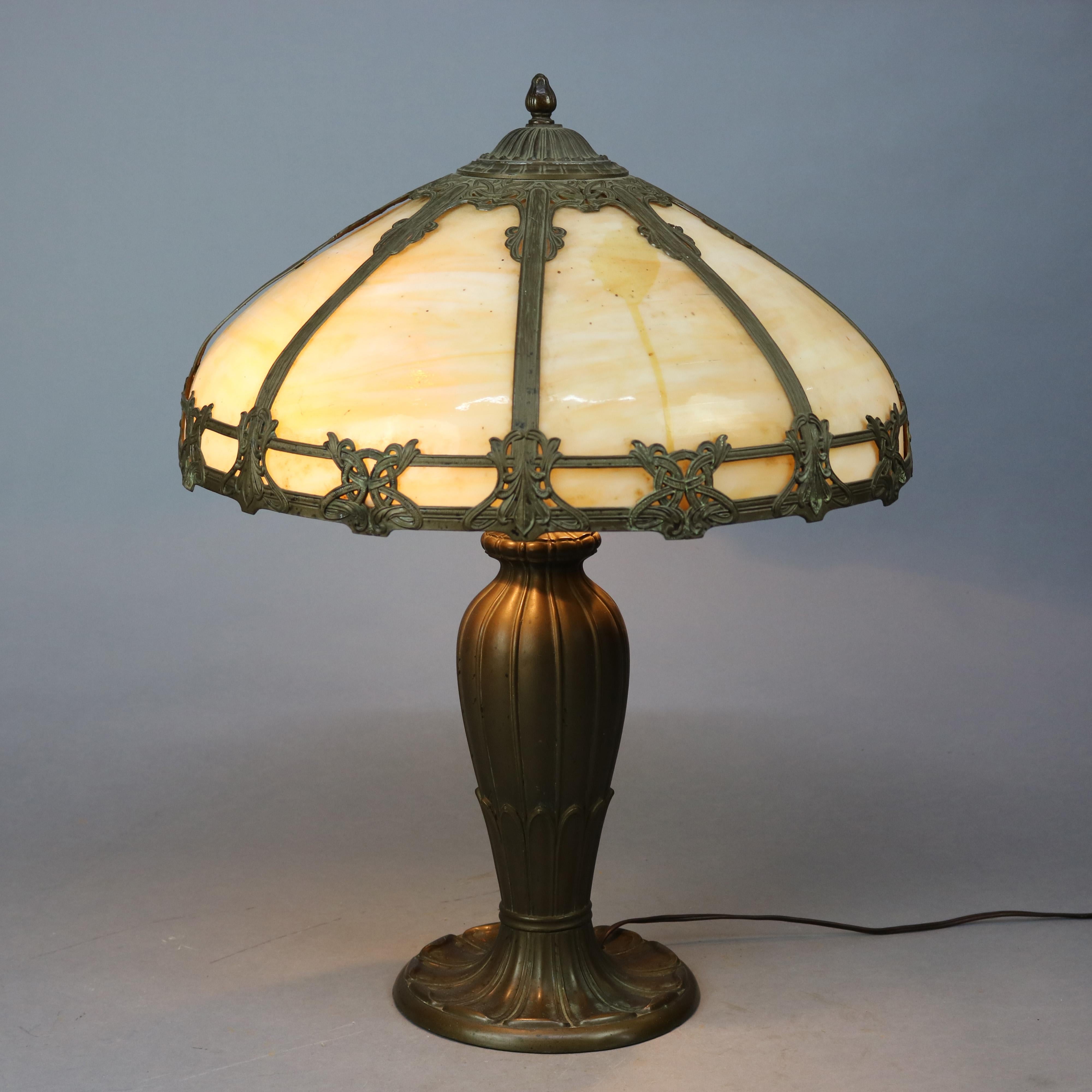An antique Arts & Crafts table lamp in the manner of Bradley and Hubbard offers dome shade with foliate cast frame housing bent slag glass panels over cast urn form double socket base, c1910
School slag glass table lamp Circa 1910

Measures -