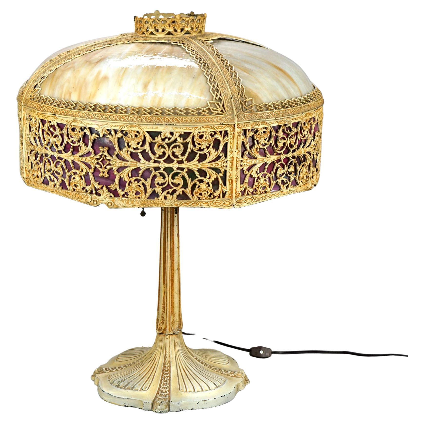 An antique Arts and Crafts table lamp in the manner of Bradley and Hubbard offers dome form cast shade with filigree foliate band and housing two-tone slag glass over double socket cast base, c1920

Measures- 22 3/4 x 17 1/2.

