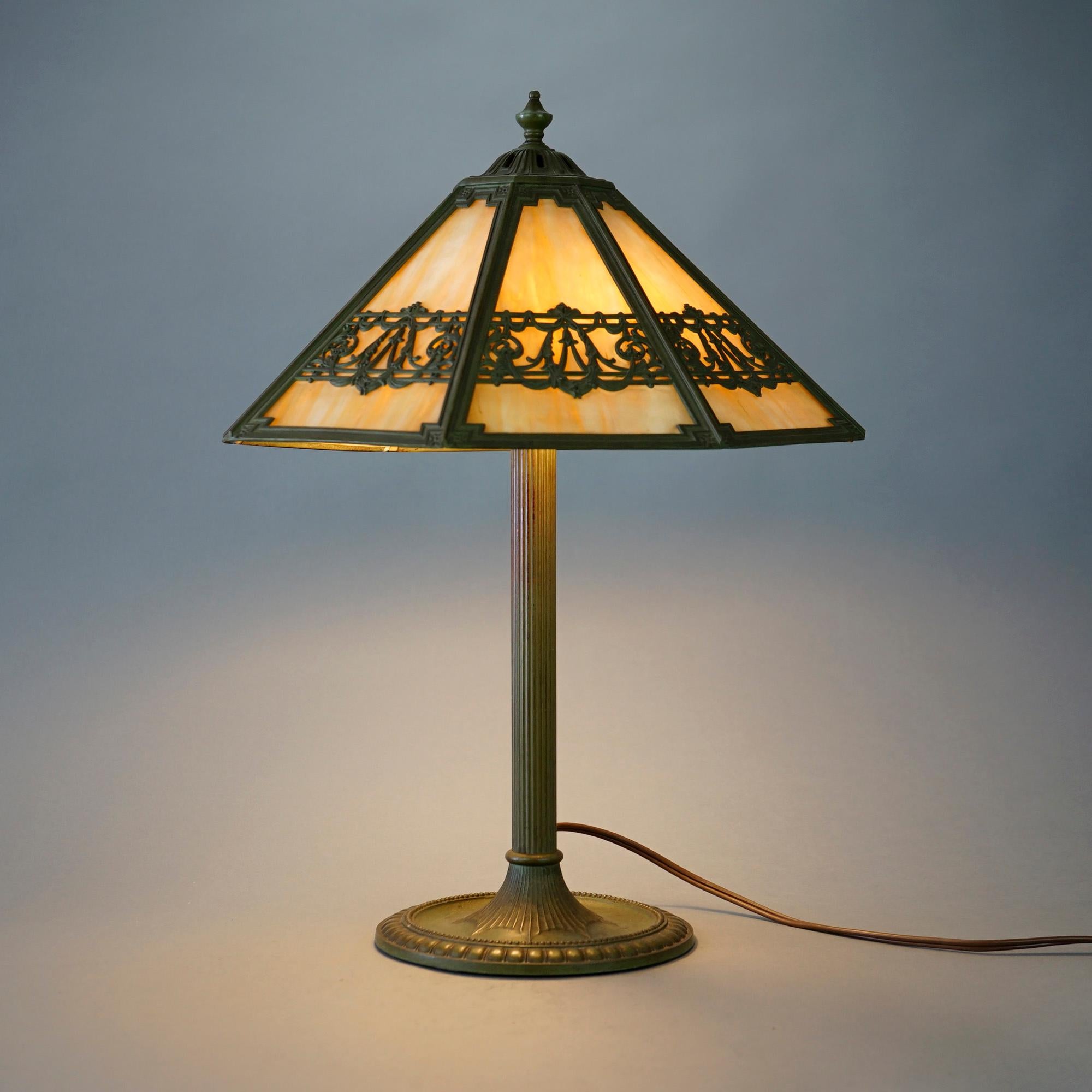 An antique Arts and Crafts table lamp by Bradley and Hubbard offers cast frame with garland and swag pattern housing slag glass panels over double socket cast base, maker signed, c1920

Measures- 21.75''H x 15''W x 15''D.