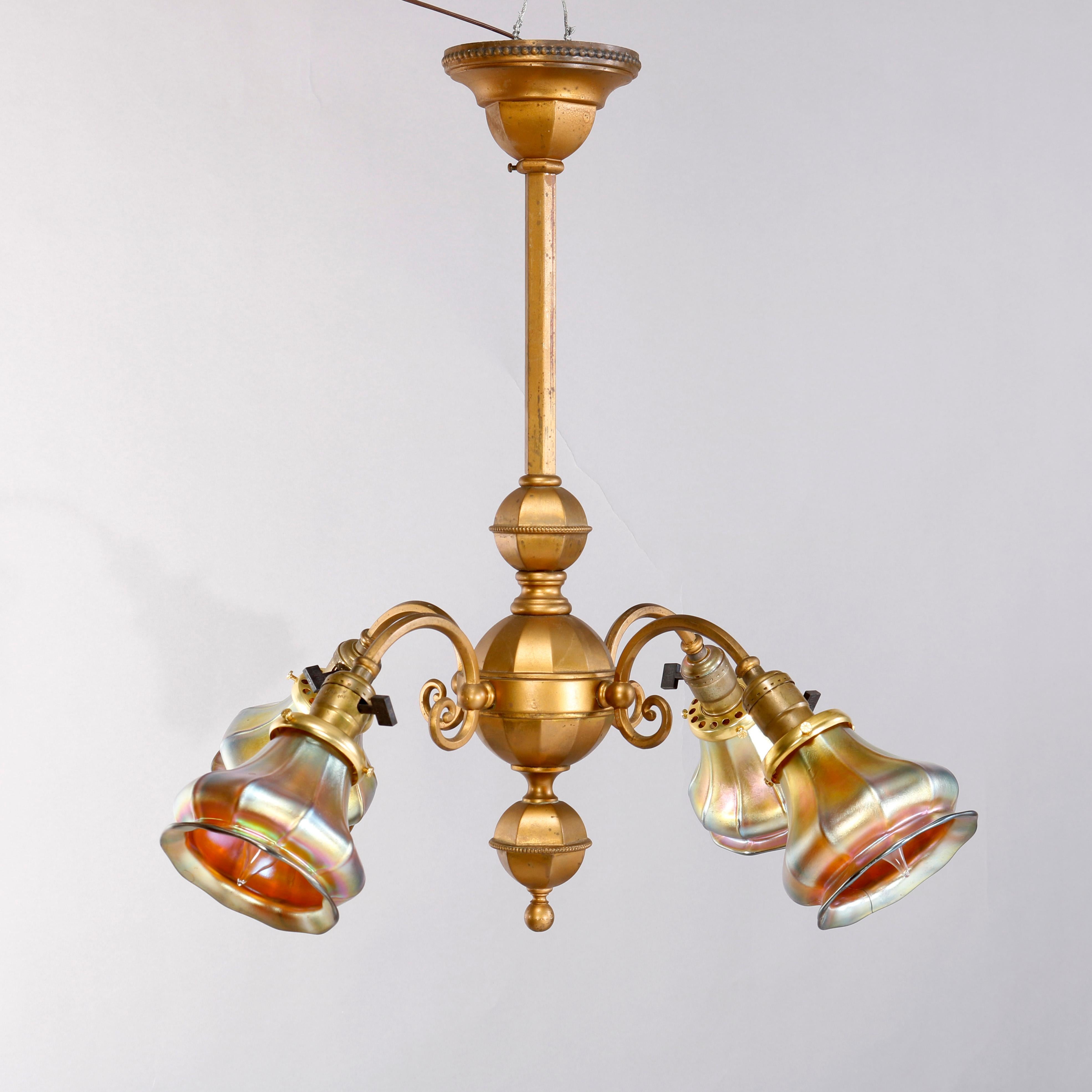An antique Arts and Crafts chandelier offers brass frame with central faceted spherical font having four scroll form arms terminating in lights with gold aurene tulip form art glass shades, c1920

Measures- 22.5''H x 21''W x 21''D.

Catalogue Note: