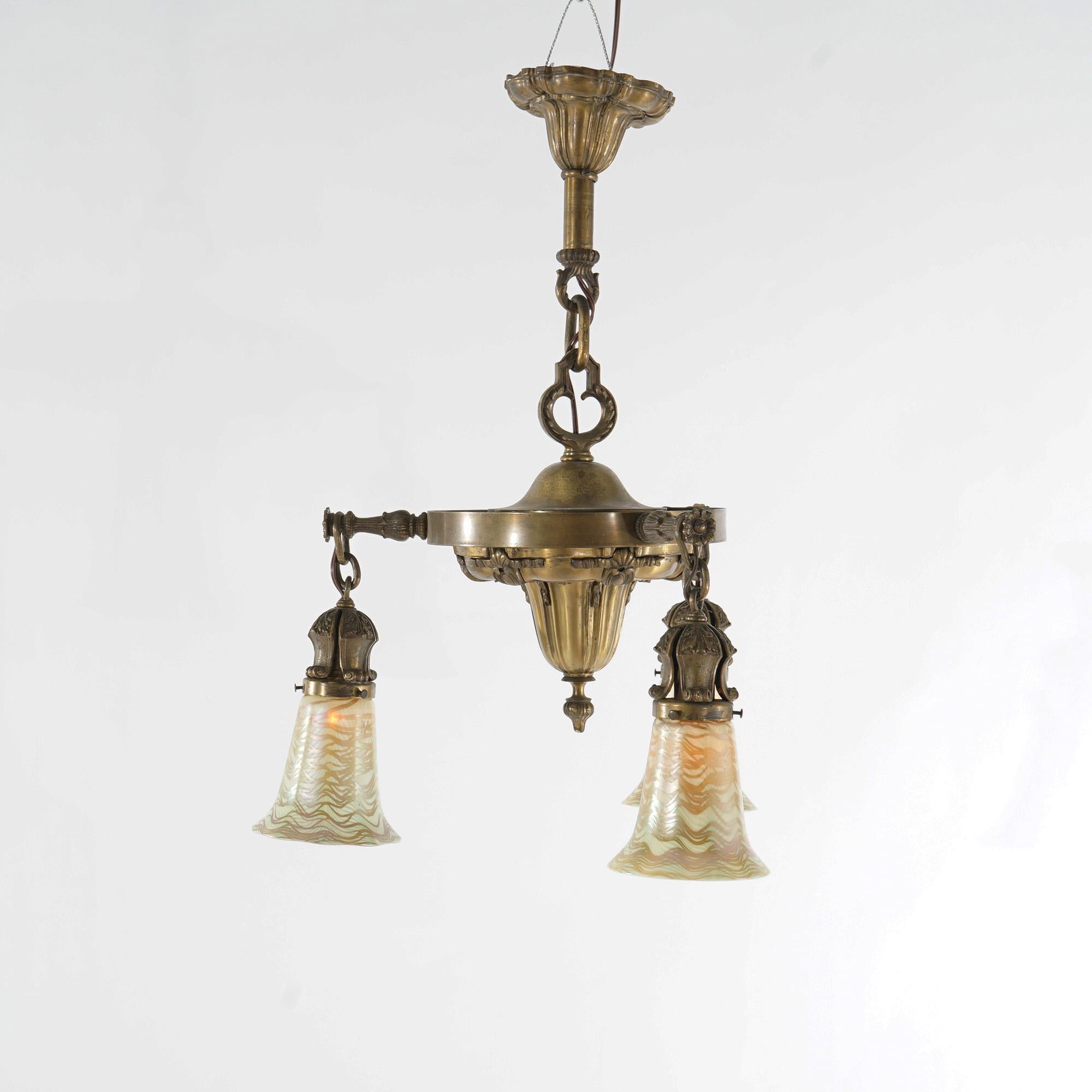 An antique Arts and Crafts chandelier offers a brass frame with three drop lights terminating in Quezal art glass shades, c1910

Measures - 27