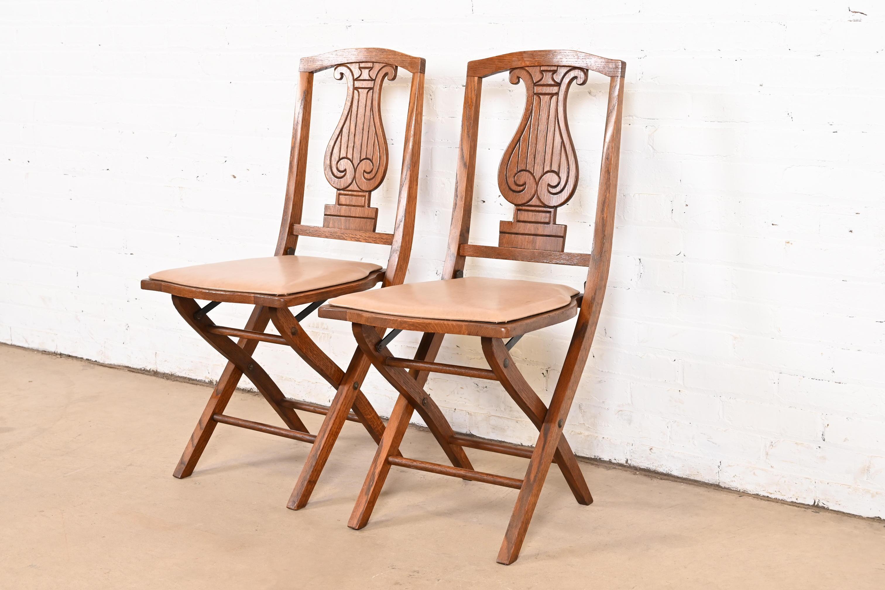 A rare and exceptional pair of Arts & Crafts period lyre back folding dining chairs or side chairs

By Phoenix Chair Company

USA, Circa 1920s

Carved oak, with tan vinyl upholstery.

Measures: 16.75