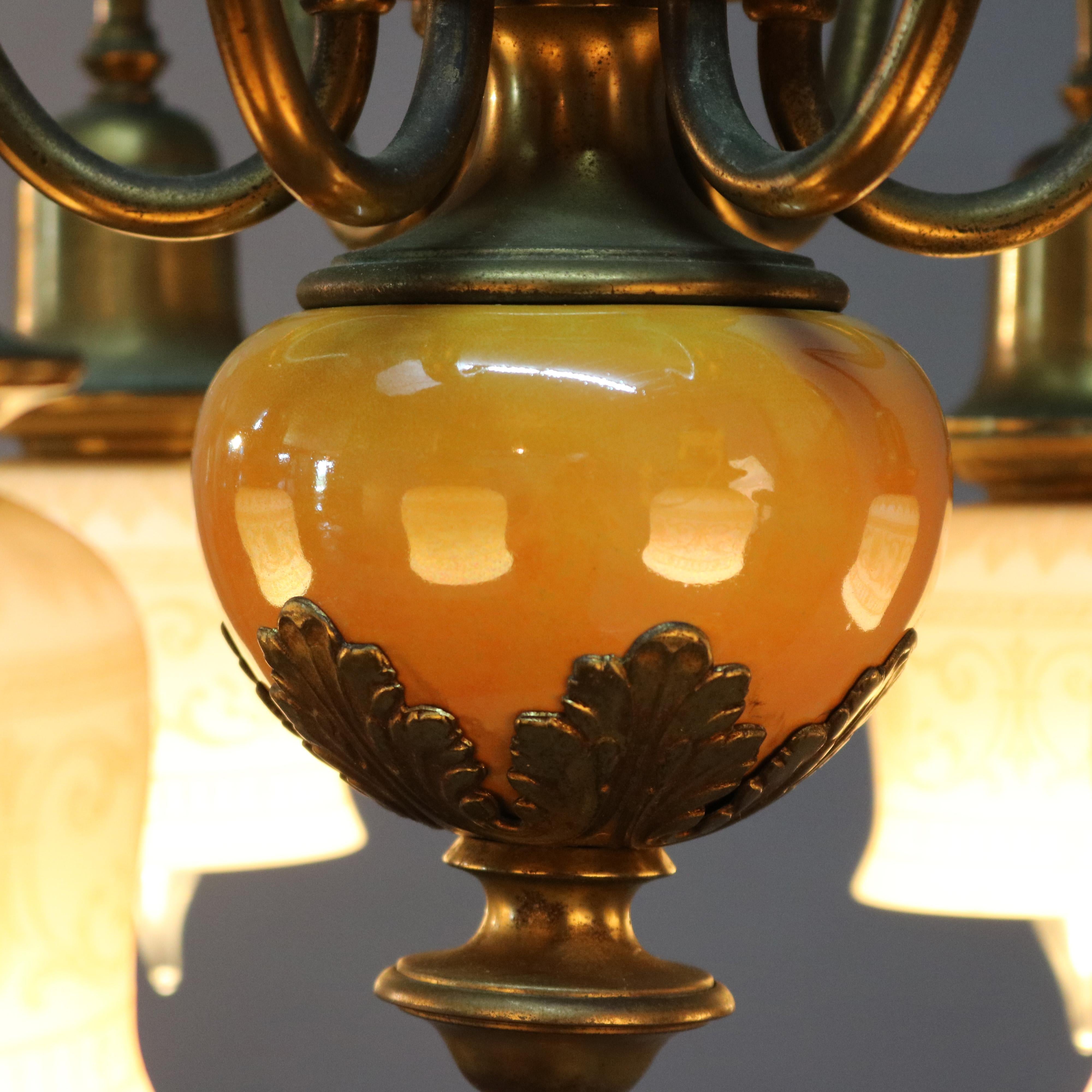 An Arts and Crafts chandelier offers brass frame with butterscotch glass font and six scroll form arms terminating in drop lights with foliate decorated etched shades, c1930

Measures: 18