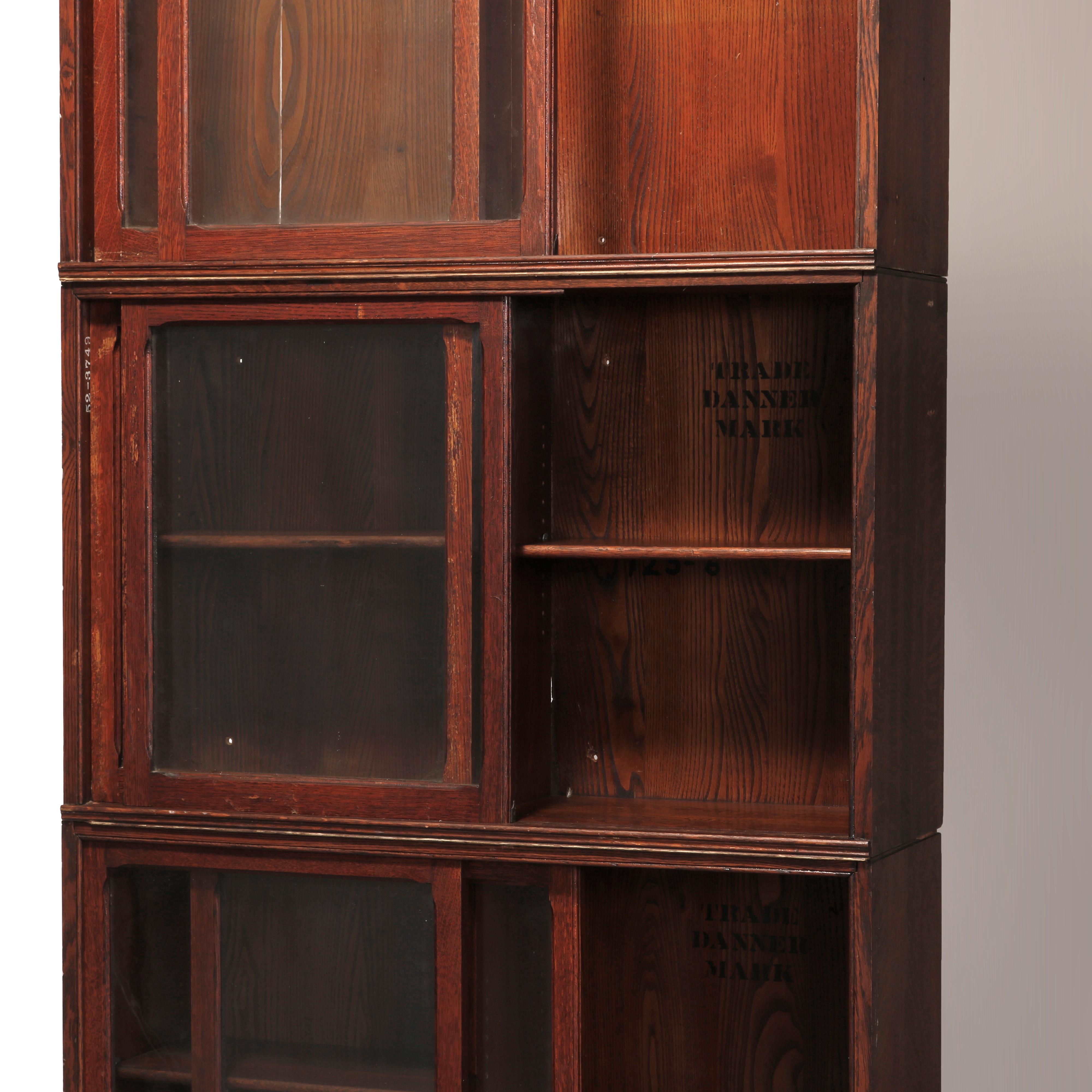 An antique Arts & Crafts Barrister bookcase by Danner offers oak construction with three stacks having sliding glass doors, maker stamp inside as photographed, circa 1910.

Measures: 82.25