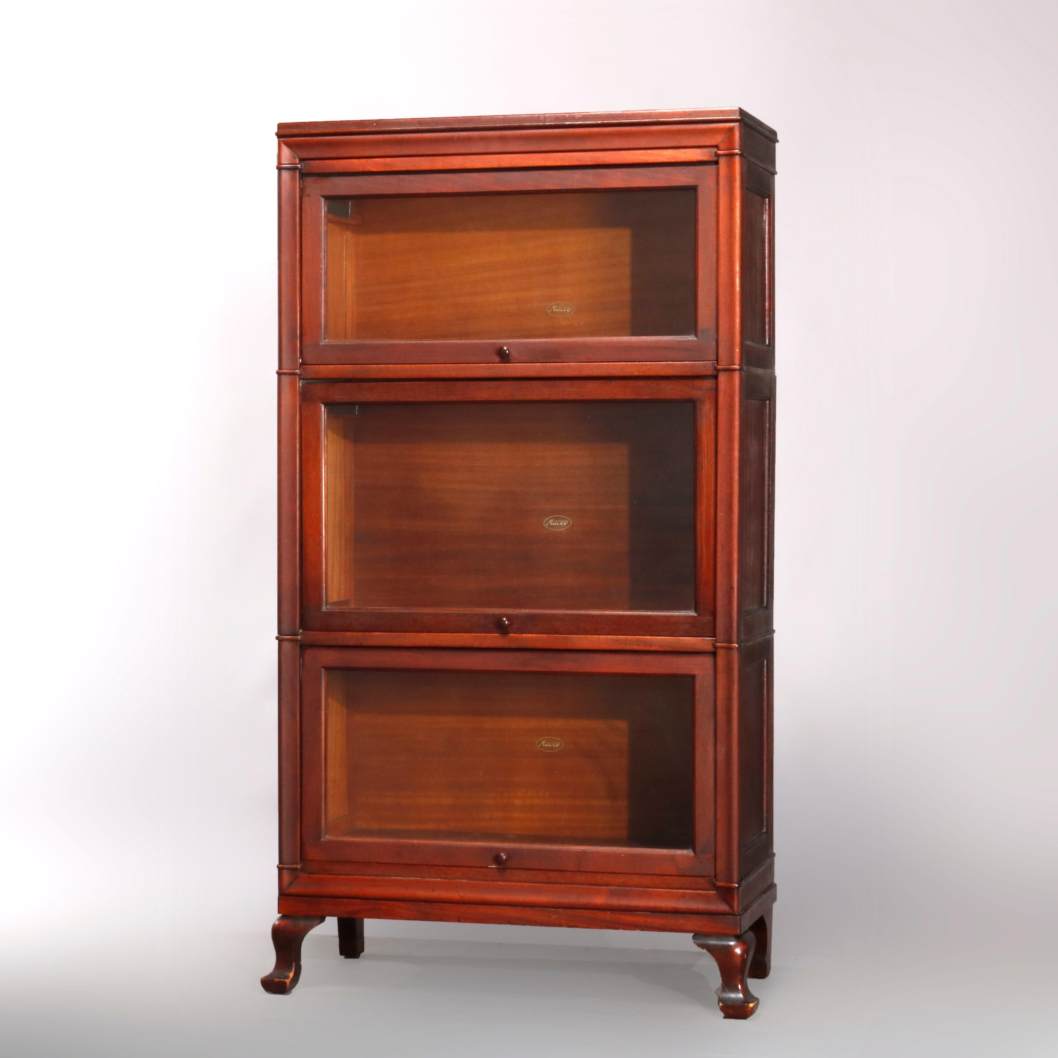 An Arts & Crafts sectional barrister bookcase by Macy, offers diminutive sizing, mahogany construction with three stacks each having a pull-down glass door raised on cabriole legs and surmounted by removable crown, maker label as photographed, circa