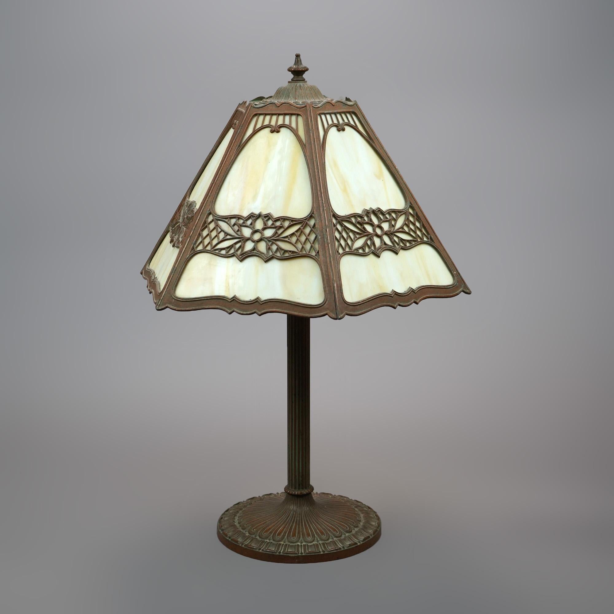 An antique Arts & Crafts table lamp by Miller offers cast filigree shade with stylized foliate design and housing slag glass panels surmounting double socket base, EM Co. mark on base as photographed, circa 1920

Measures - 24.25