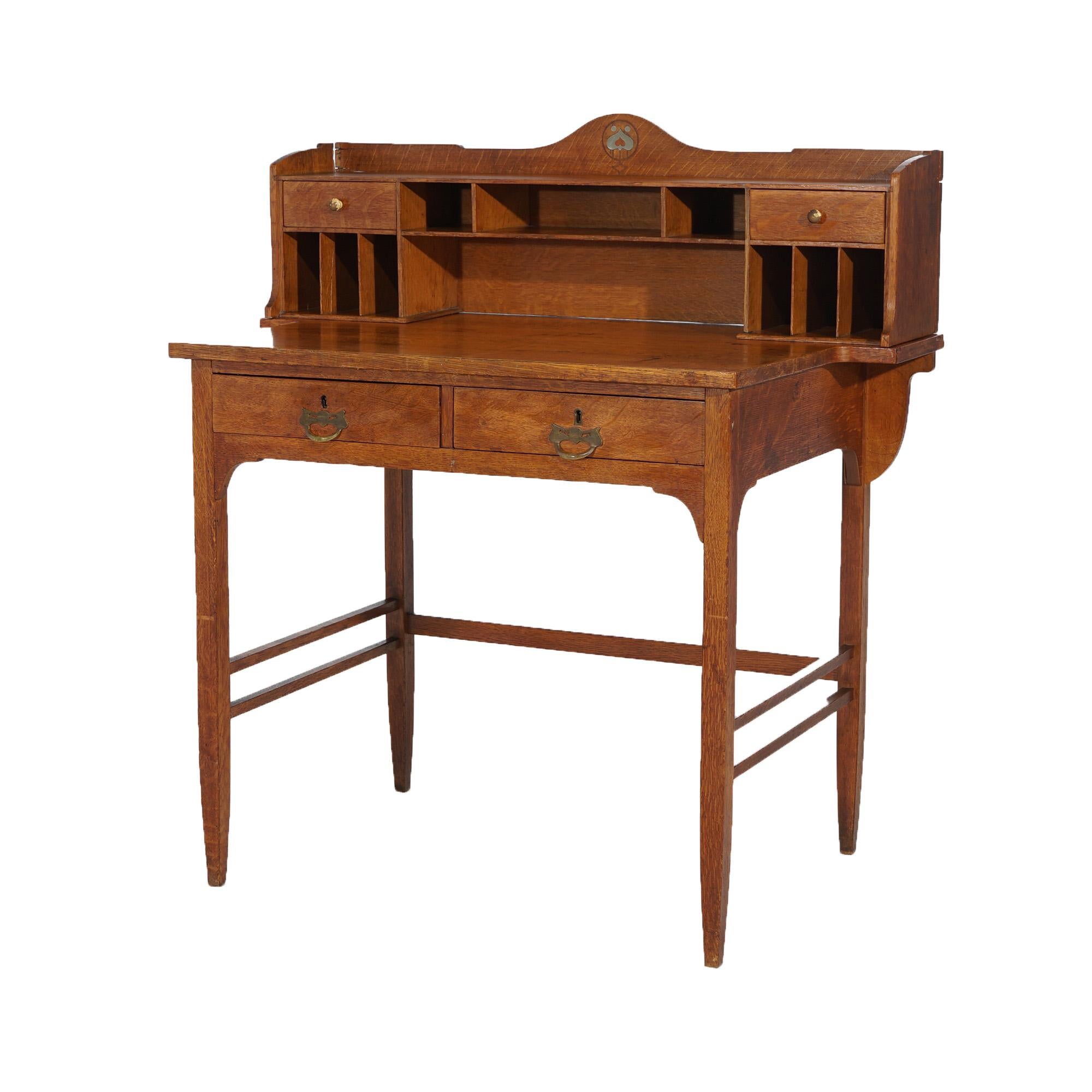 An antique English Arts & Crafts post card desk in the manner of Liberty & Co. offers oak construction with upper having shaped backsplash, pigeon holes and drawers over double drawer case raised on straight and square legs, maker label as