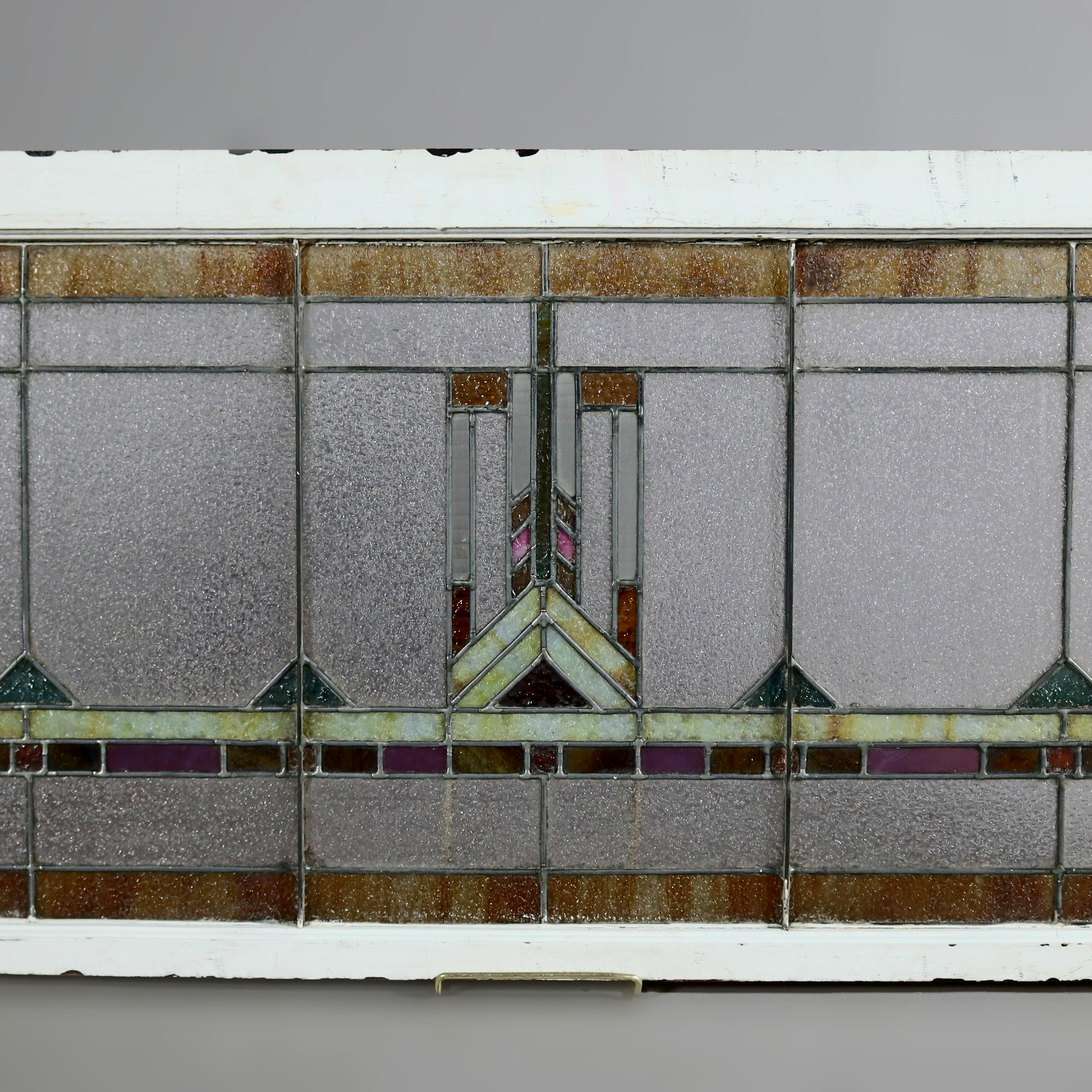 An Arts & Crafts Frank Lloyd Wright style window panel offers leaded stained glass in geometric form and having central stylized feather pattern, encased in wood window sash, circa 1910.

Measures: overall 46.5