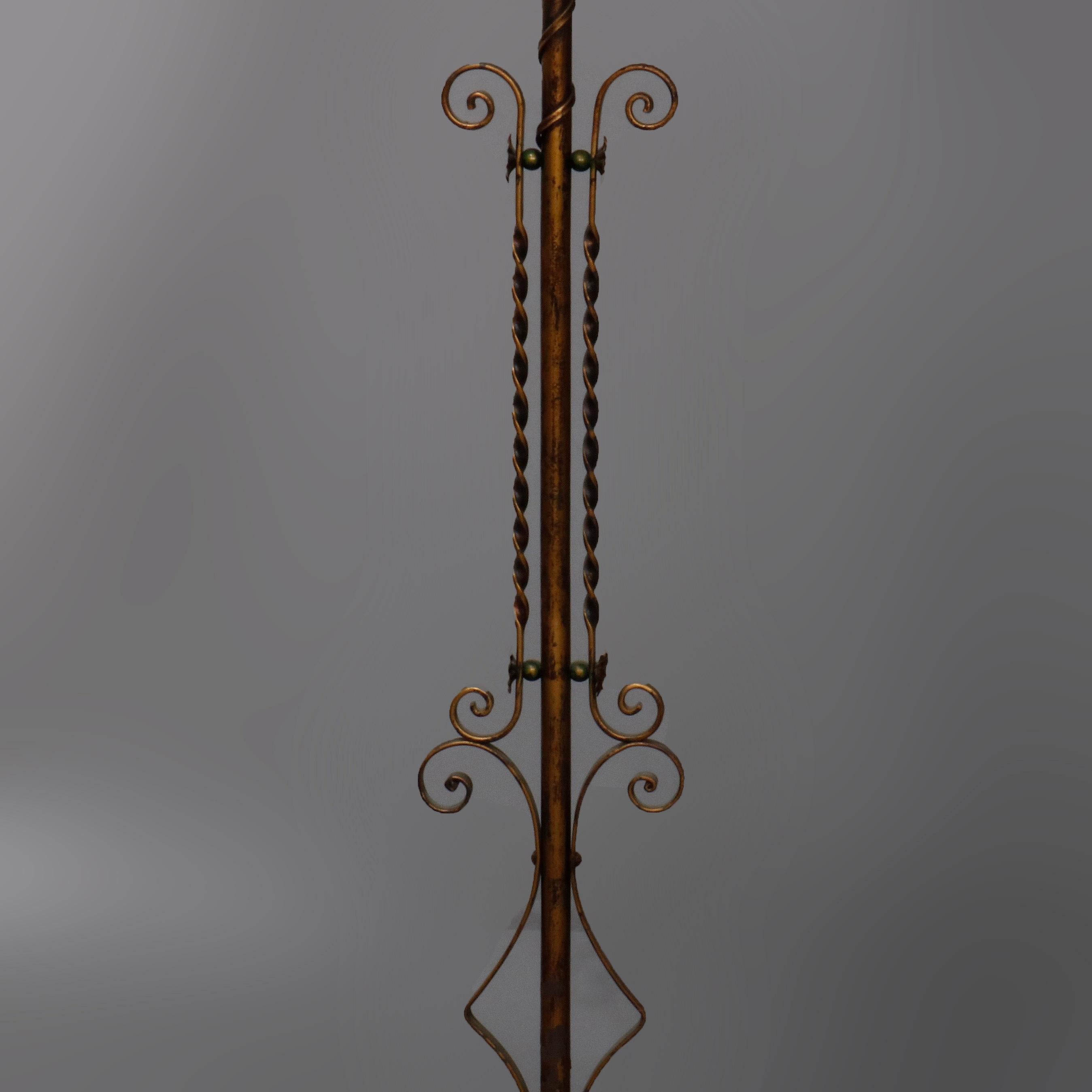 An antique Arts & Crafts floor lamp offers wrought iron construction with gilt finish, foliate and scroll accents, flanking twisted and scroll elements and goose neck terminating in a light with art glass shade, circa 1920

Measures: 58.5