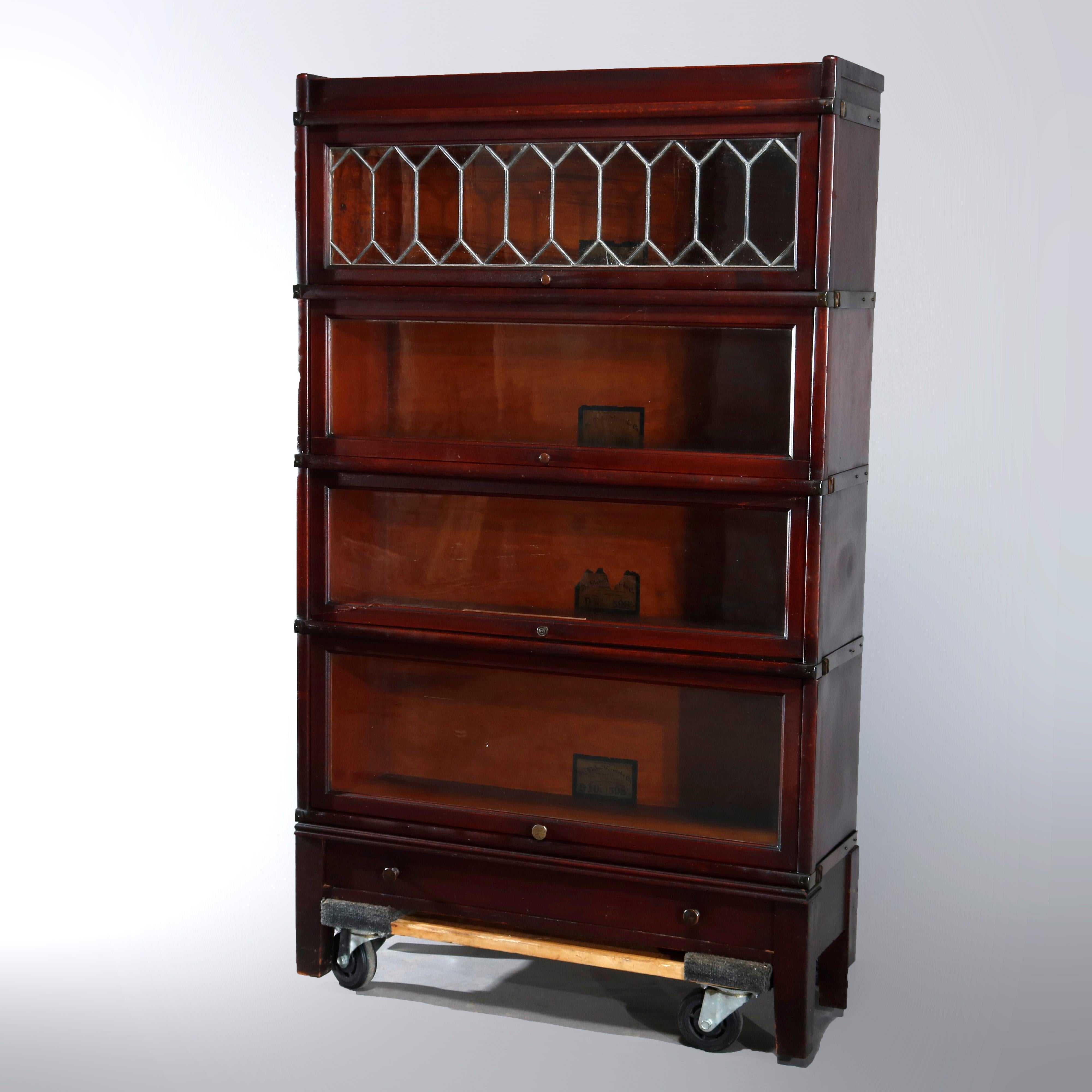 An antique Arts & Crafts Barrister bookcase by Globe Wernicke offers mahogany construction with four stacks, the top having leaded glass door, raised on square legs and having lower drawer, original labels as photographed, circa 1910.

Measures: