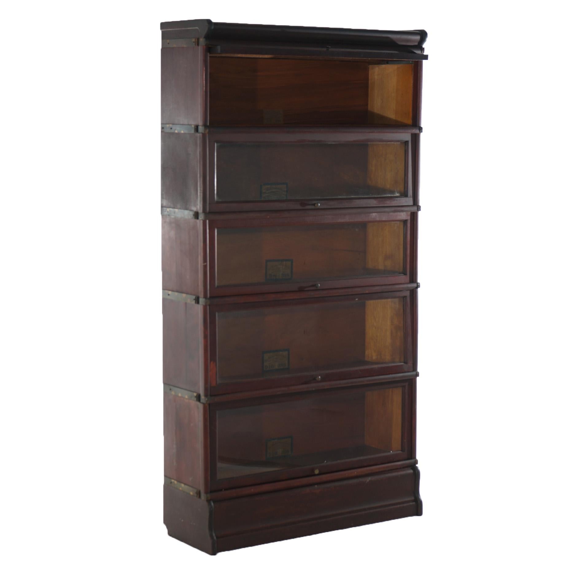 An antique Arts & Crafts bookcase by Globe Wernicke offers mahogany construction with five stacks, each having pull-out glass doors and raised on an ogee base, maker label as photographed., c1910

Measures - Overall 66.5''H x 34''W x 12.5''D; three