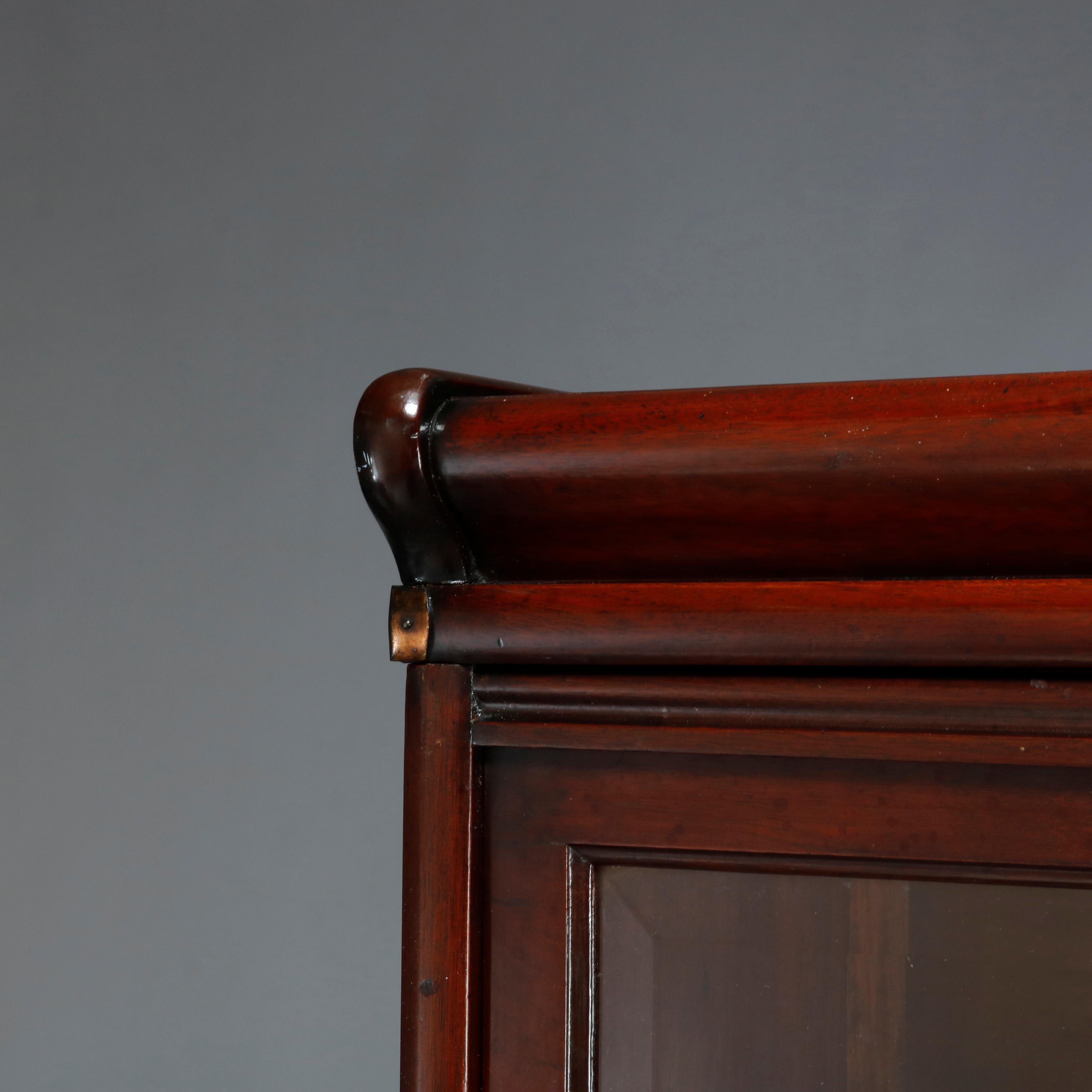 An antique Arts and Crafts barrister bookcase by Globe Wernicke offers mahogany construction with five stacks having pull-out glass doors and seated on ogee base, label remnant in gold on crest as photographed, c1920.

Measures: 72.75