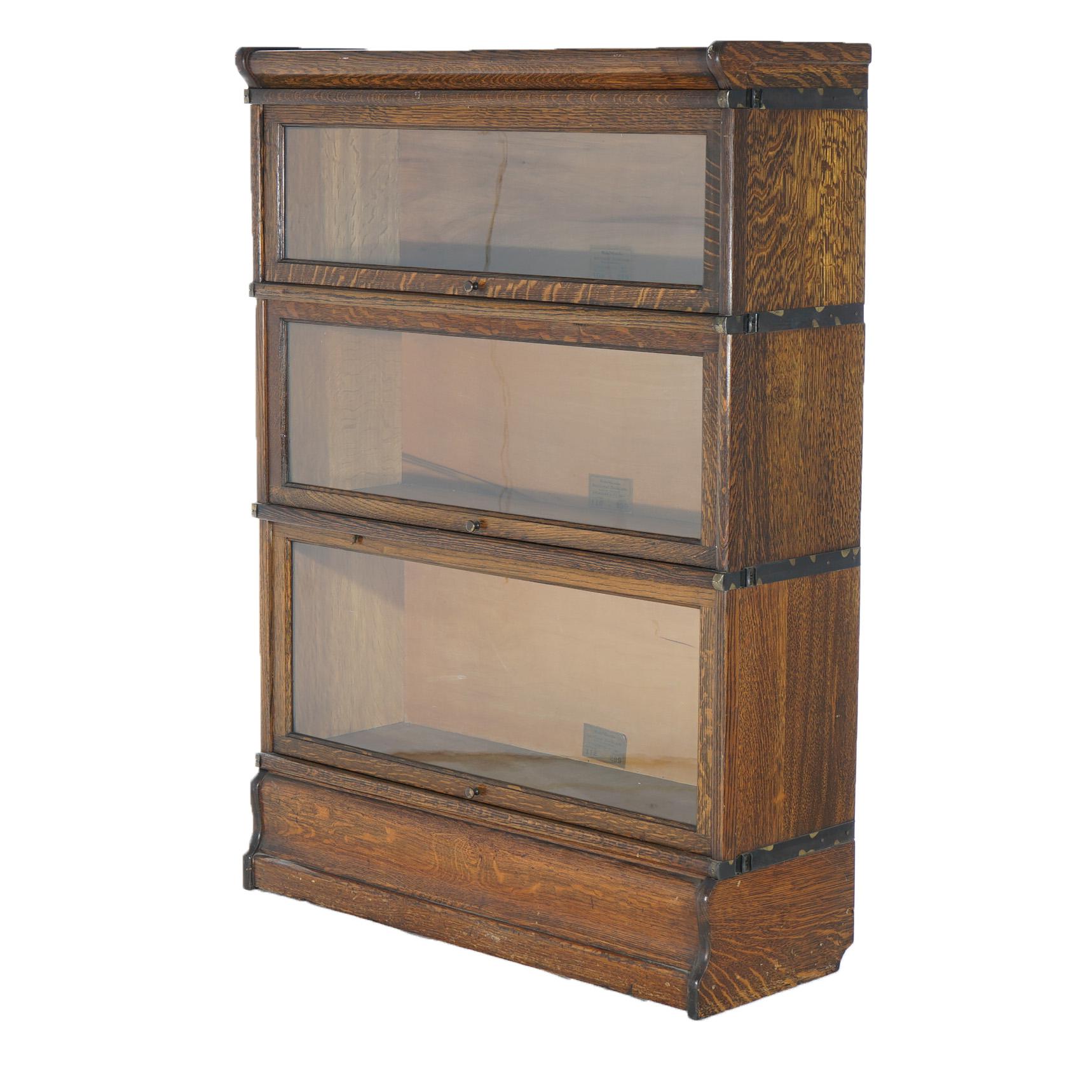 An antique Mission Arts and Crafts barrister bookcase by Globe Wernicke offers quarter sawn oak construction with three stacks, each having a pull-out glass door, raised on an ogee base; maker labels as photographed; c1920

Measures - 47