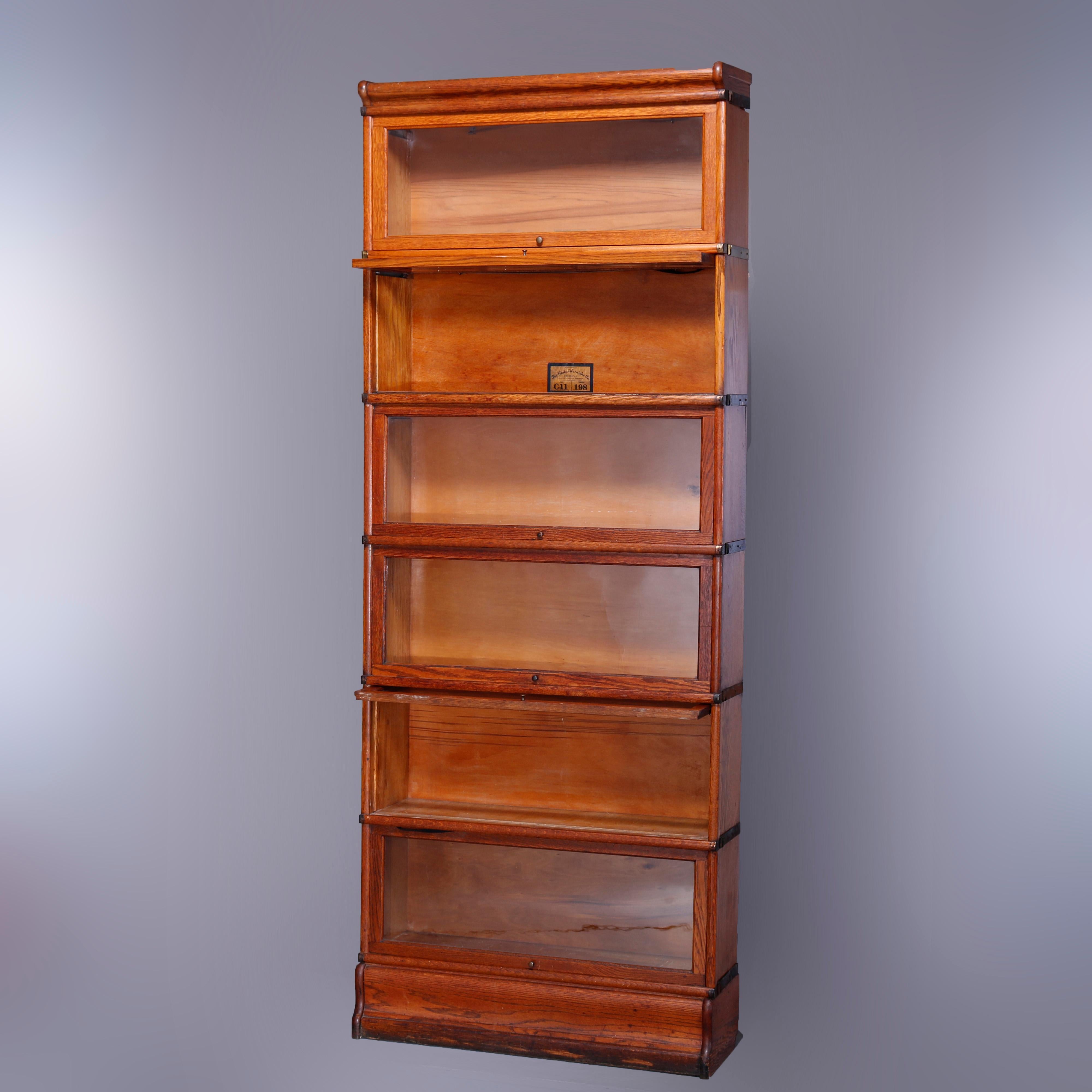 An antique Arts & Crafts barrister bookcase by Globe Wernicke offers quarter sawn oak construction with six stacks, each with pull-out glass doors, raised on ogee base, original labels as photographed, c1910

Measures - 88.25'' H x 34'' W x 11'' D;