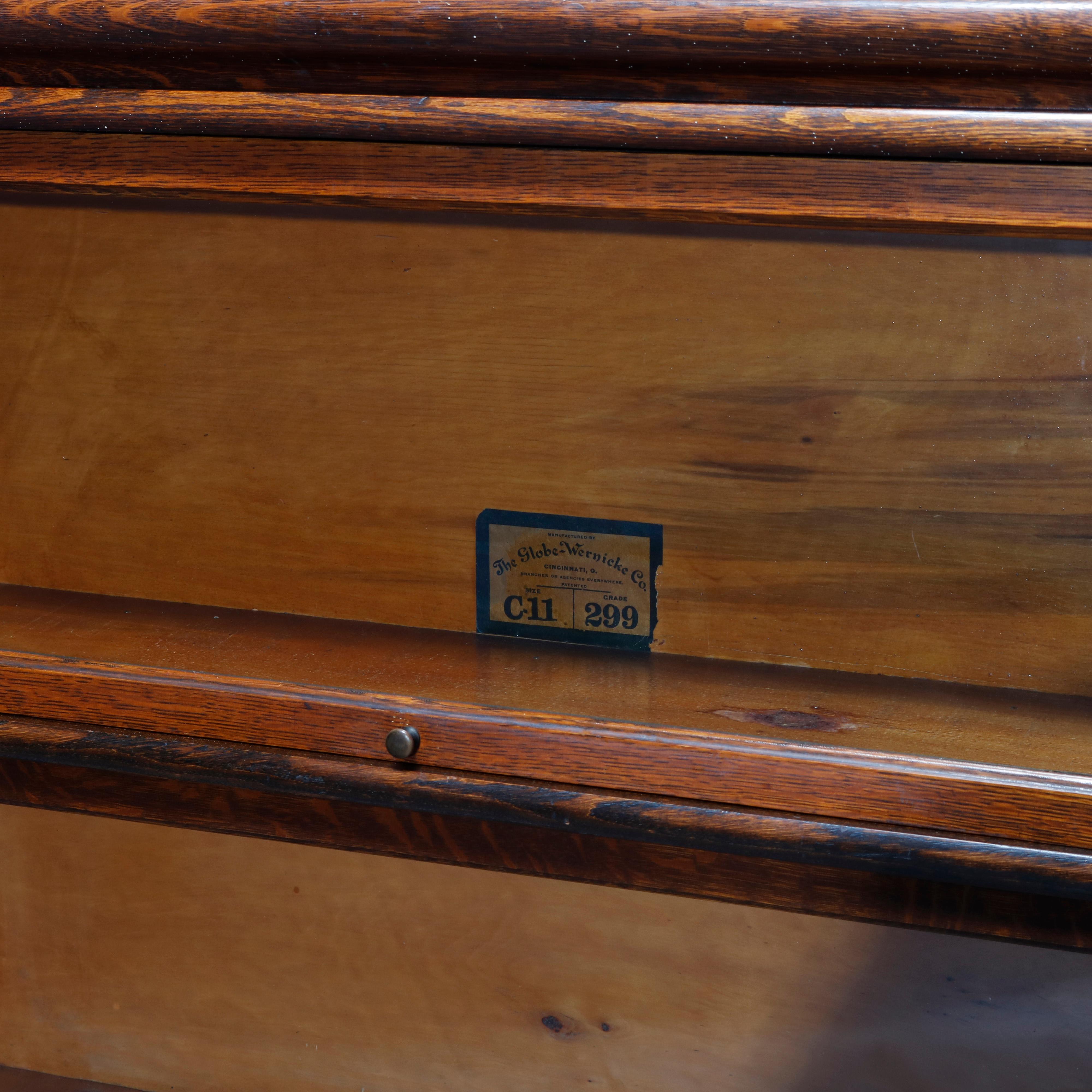 An antique Arts and Crafts barrister bookcase by Globe Wernicke offers oak construction with three stacks having pull-out glass doors and raised on ogee base, original maker label as photographed, c1910.

Measures: 51.5