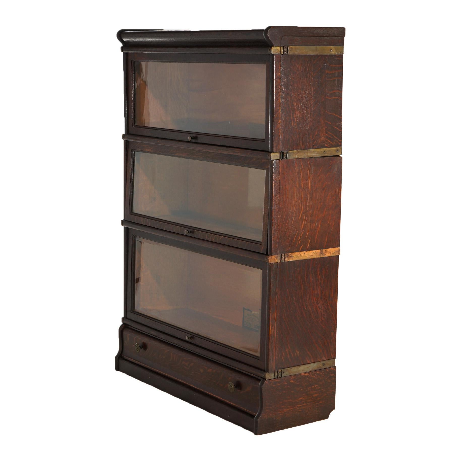 An antique Arts and Crafts barrister bookcase by Globe Wernicke offers oak construction with three pull-out glass doors, raised on an ogee base having a single long drawer; maker labels as photographed; c1910

Measures - 49