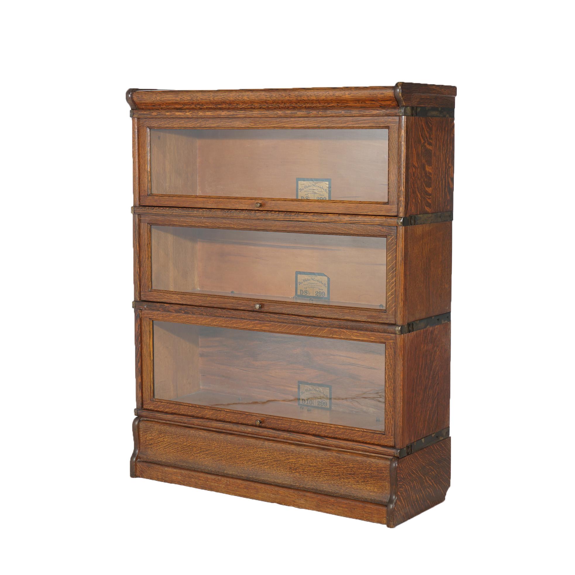 An antique Arts and Crafts barrister bookcase by Globe Wernicke offers quarter sawn oak construction with three stacks, each having pull-out glass doors, raised on an ogee base; maker labels as photographed; c1910

Measures - 43.5