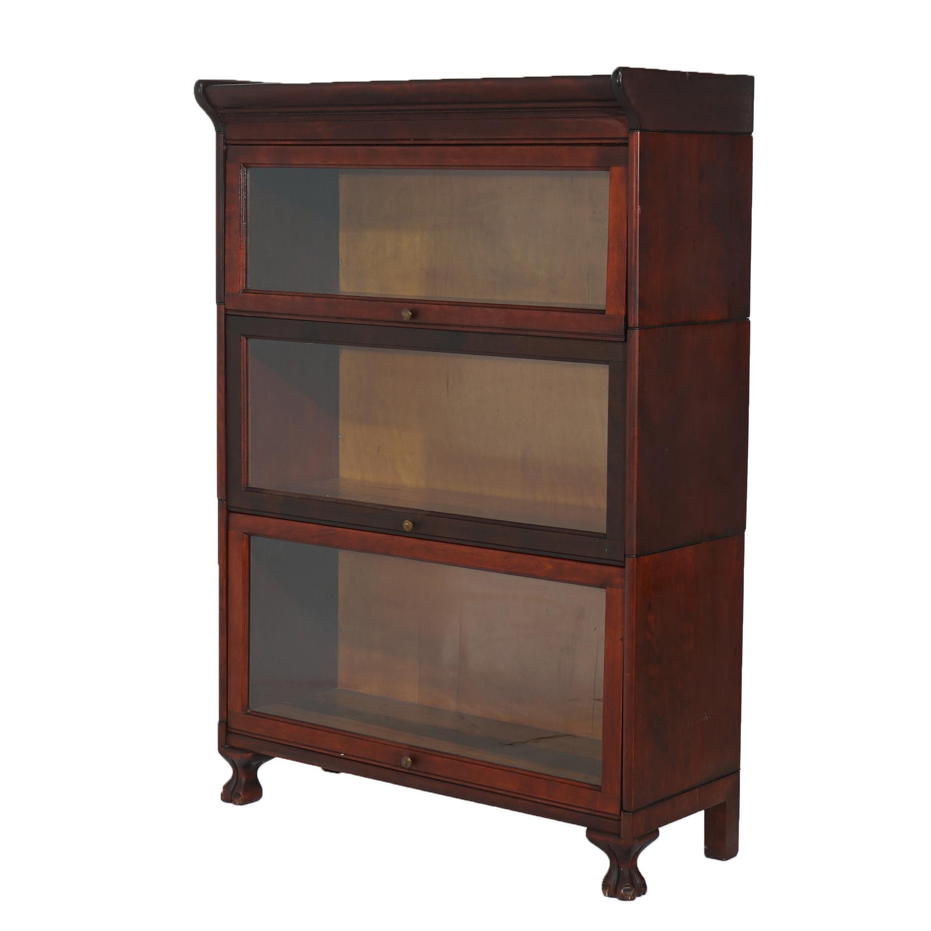 ***Ask About Discounted In-House Shipping***
An antique Arts and Crafts barrister bookcase attributed to Gunn offers mahogany construction with three stacks, each having a pull-out glass door and raised on stylized paw feet; maker label as