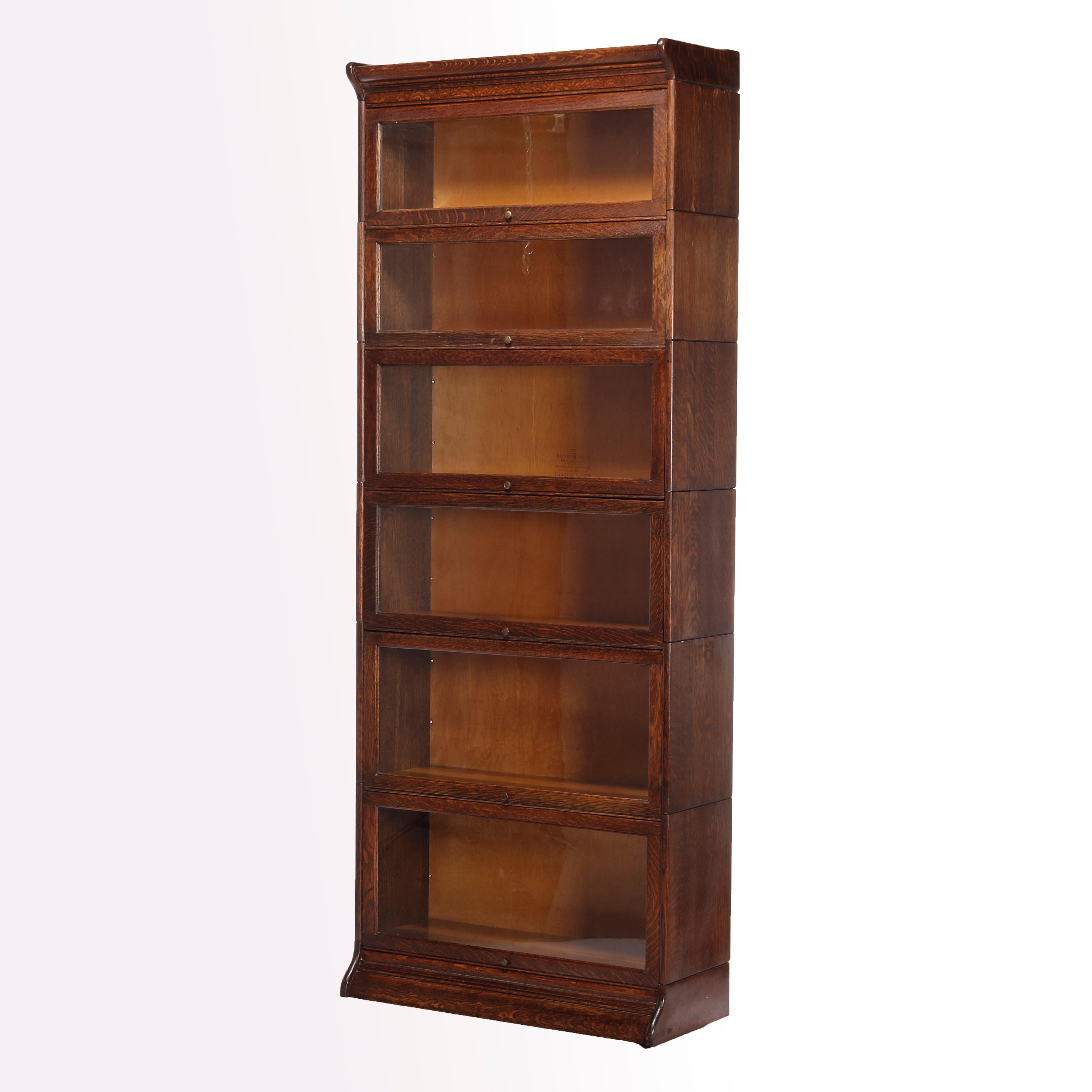 An antique Arts & Crafts sectional barrister bookcase by Gunn offers quarter sawn oak construction with six sections each having pull out glass doors and raised on ogee base, maker labels as photographed, c1910

Measures- 88'' H x 34.25'' W x 14.5''