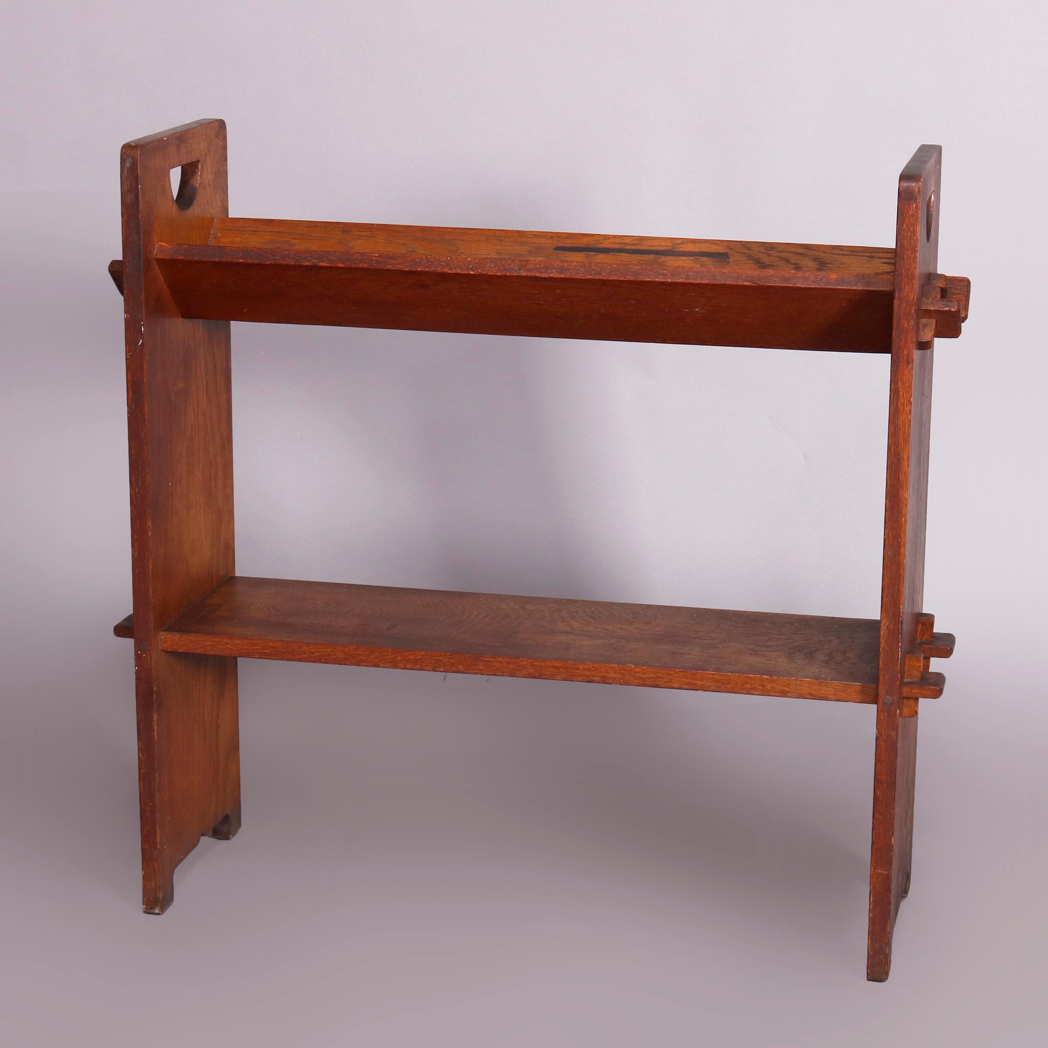 An antique Arts & Crafts Mission oak book stand by Gustav Stickley offers quarter sawn sides having cut-out D-handles with v-form trough upper and flat lower mortise and tenon shelves, circa 1910.

Measures: 30.75