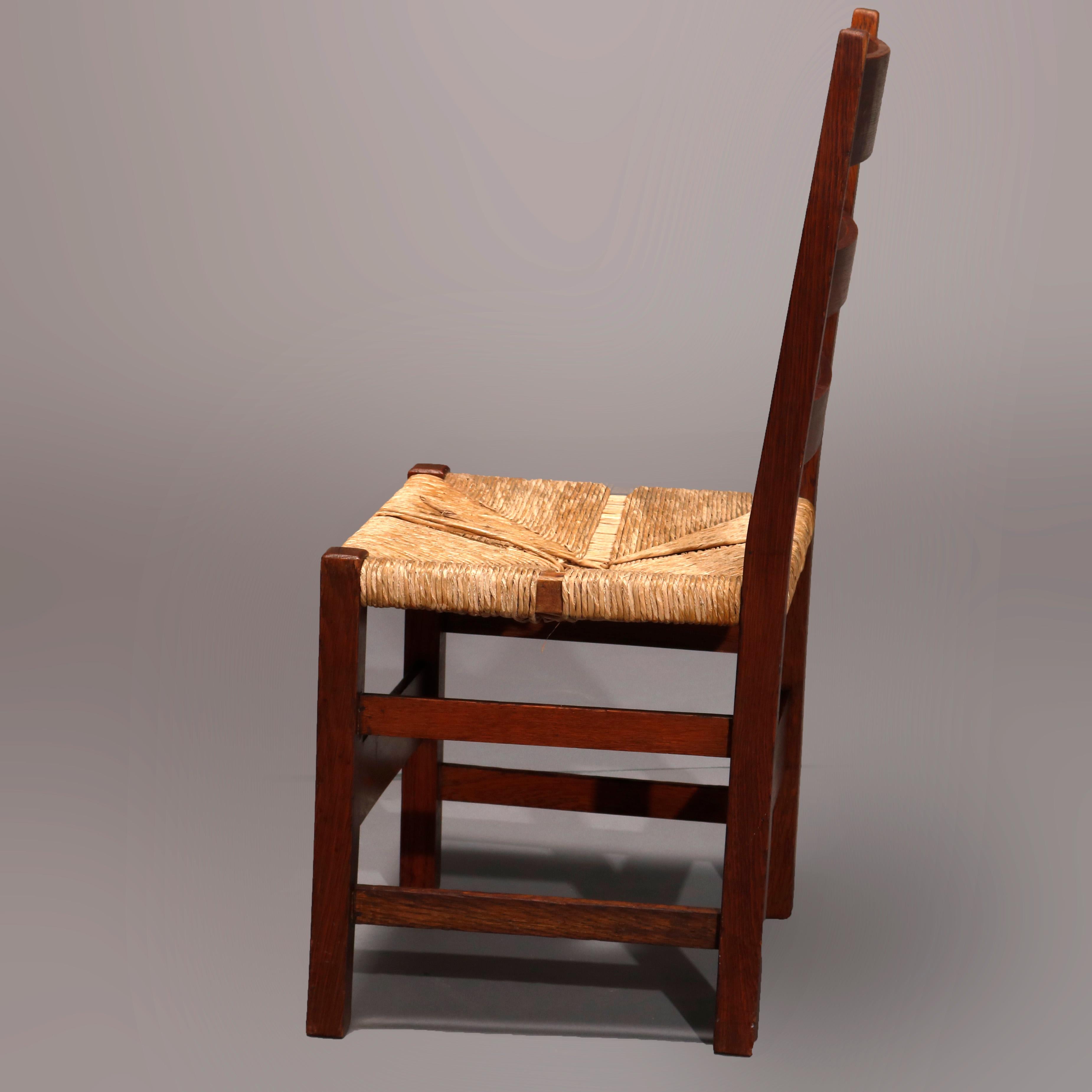 An antique Arts & Crafts Mission side chair by Gustav Stickley offers oak construction with ladder back surmounting rush seat raised on square and straight legs, circa 1910.

Measures: 34.25