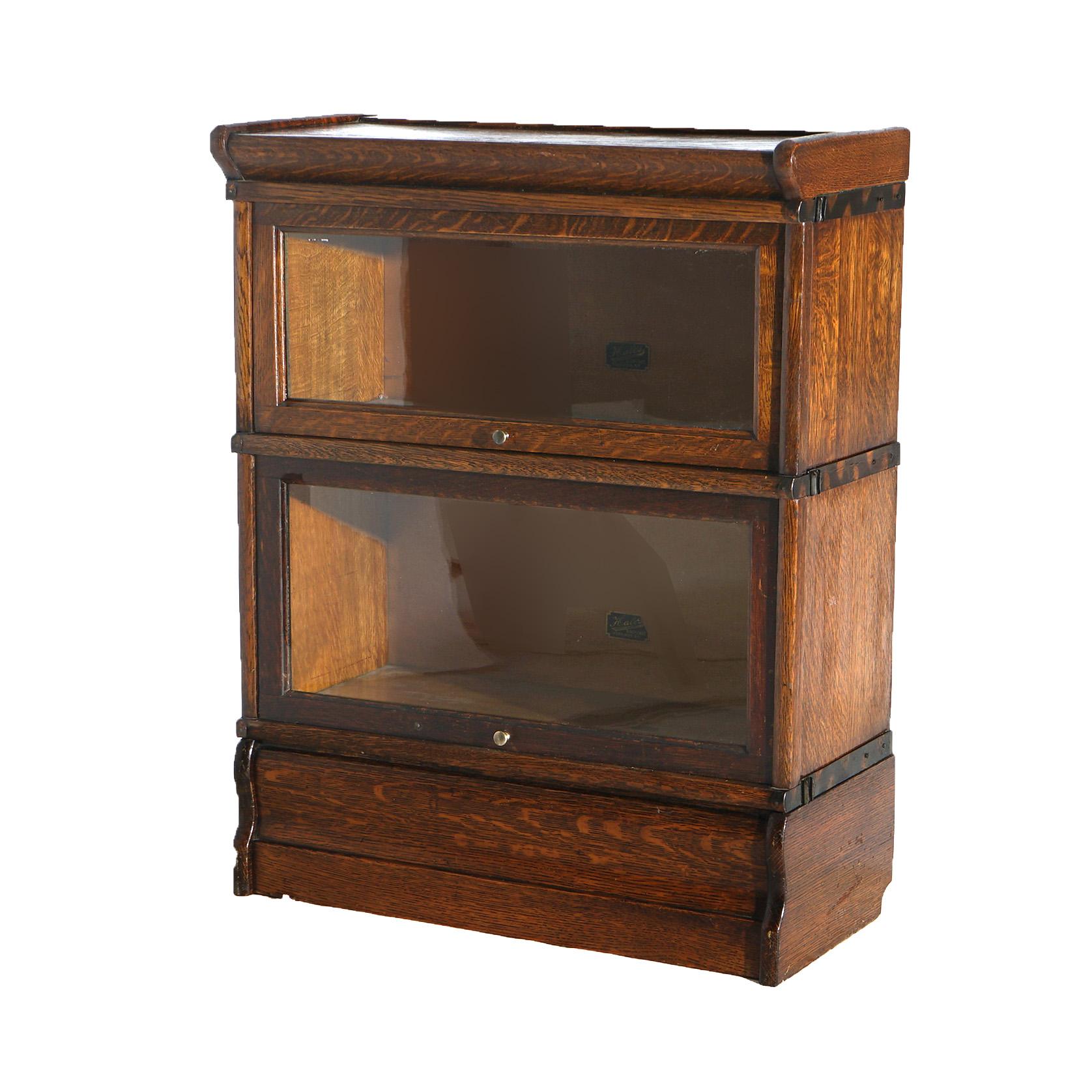 An antique Arts and Crafts barrister bookcase by Hale's offers quarter sawn oak construction with two stacks, each having pull out glass doors, raised on an ogee base and maker labels as photographed, c1920

Measures - 33