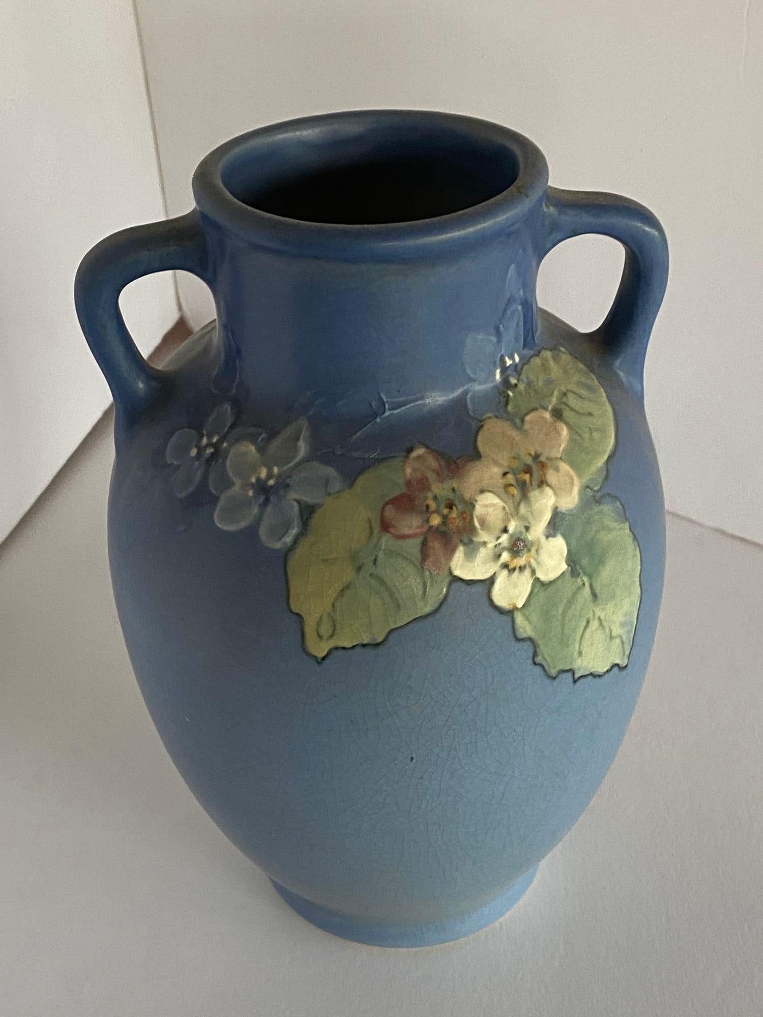 Antike Arts & Crafts Vase von Weller Pottery mit rosa und weißem Blumenmuster auf grünem bis blauem Grund, signiert von Künstler und Hersteller, um 1920.

Maße: 9,75