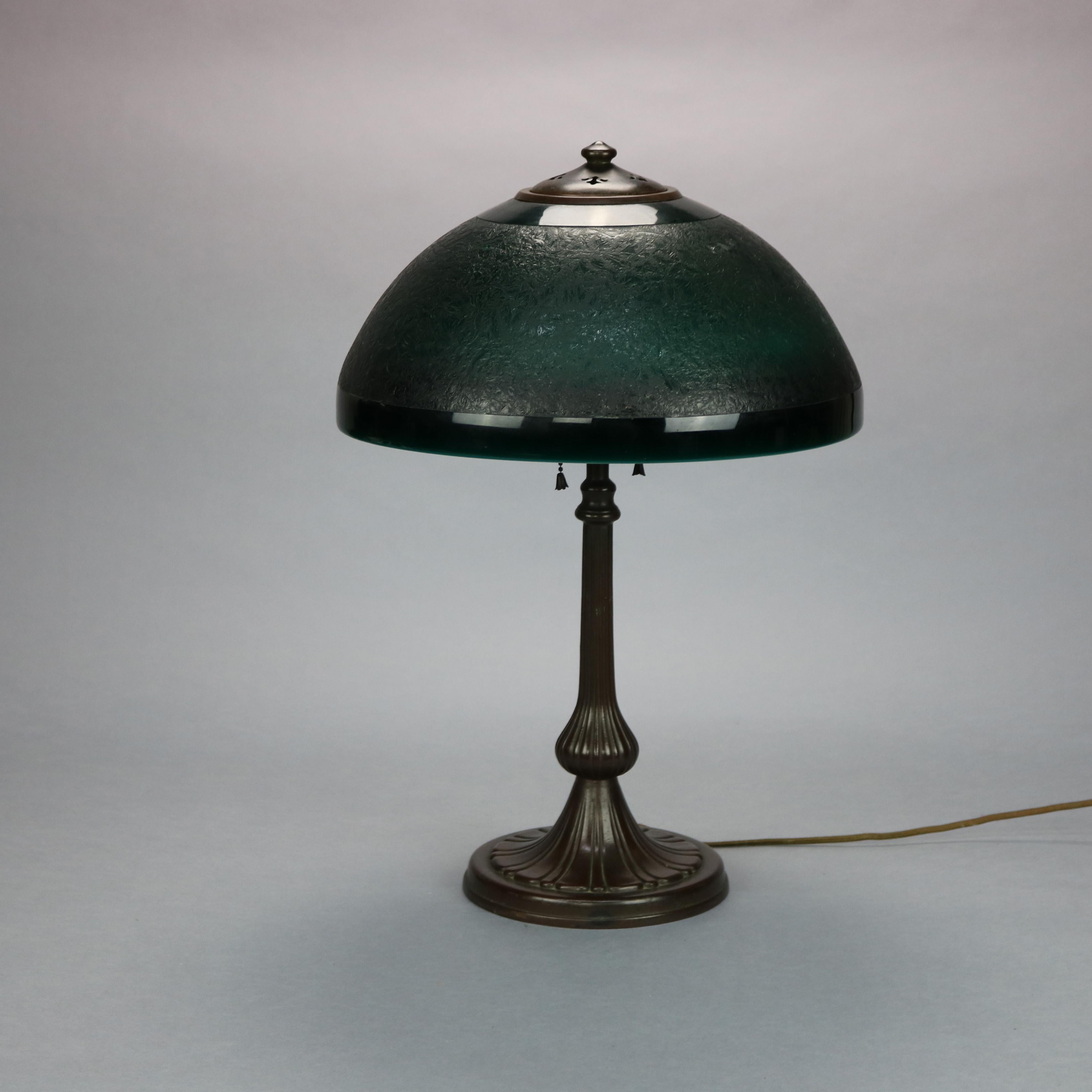 An antique Arts and Crafts table lamp by Handel offers emerald green chipped ice dome shade surmounting double socket cast base, signed on shade as photographed, c1920.

Measures: 21