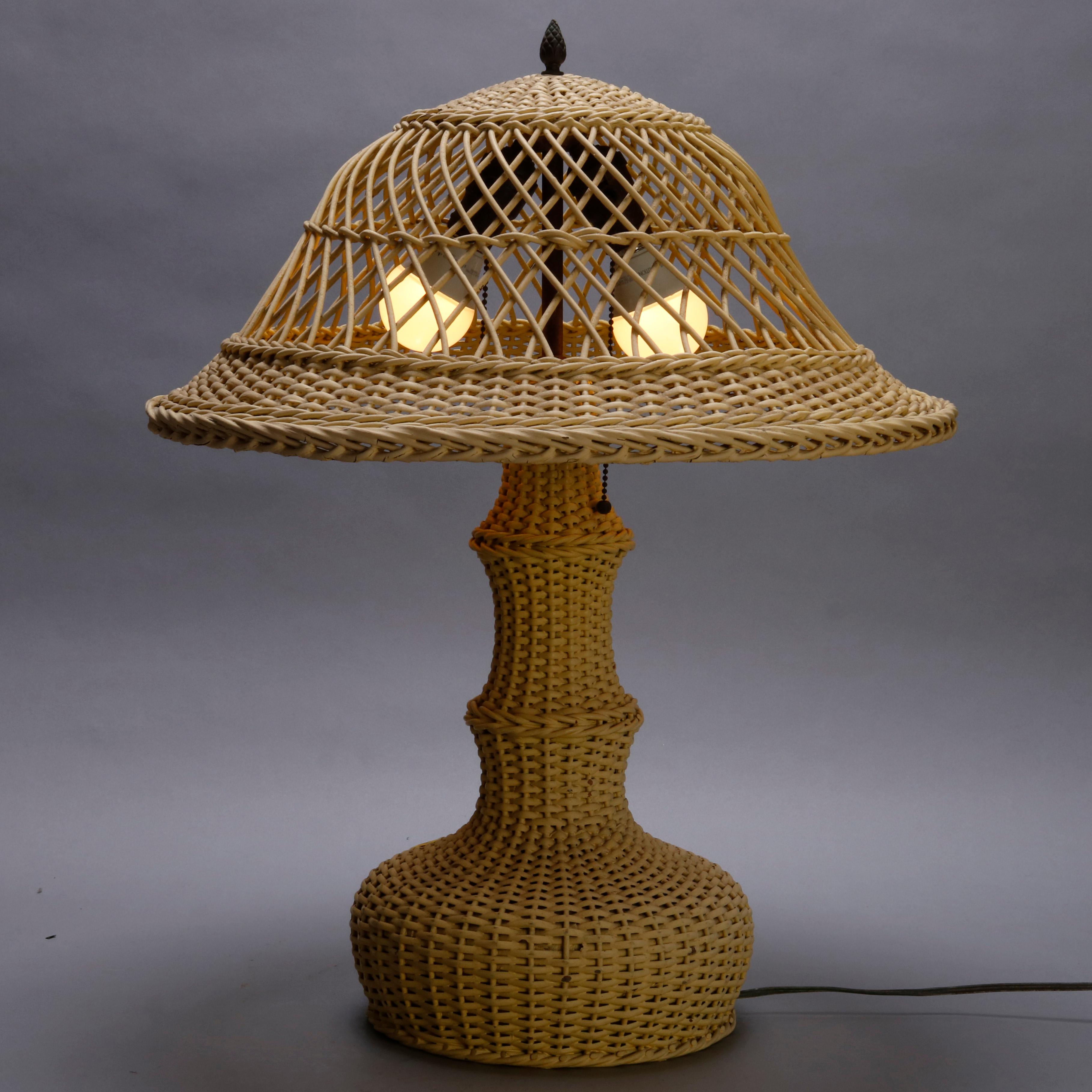 An antique Arts & Crafts Heywood Wakefield School table lamp offers painted wicker construction with open weave dome form shade with acorn finial over bottle form double socket base, circa 1920

***DELIVERY NOTICE – Due to COVID-19 we are employing