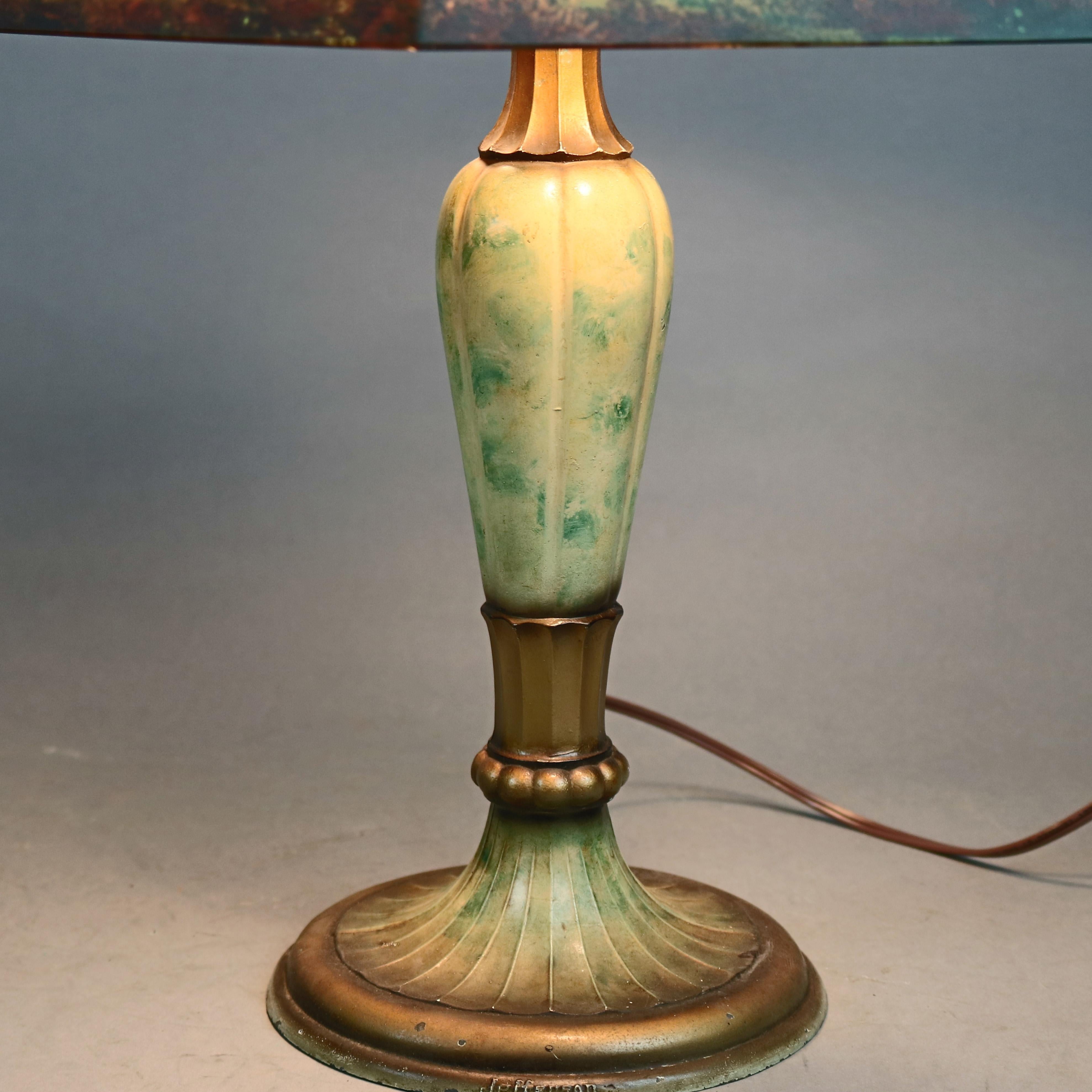 An antique Arts & Crafts Jefferson table lamp offers hexagonal reverse painted shade with landscape scene surmounting double socket base, circa 1920

Measures: 22