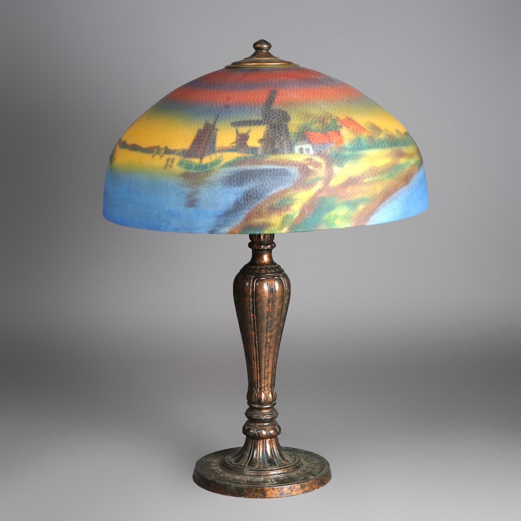 An antique Arts and Crafts Jefferson table lamp offers glass shade in dome form with reverse painted countryside scene having lake and country road, over cast double socket base, c1920

Measures - 23.25