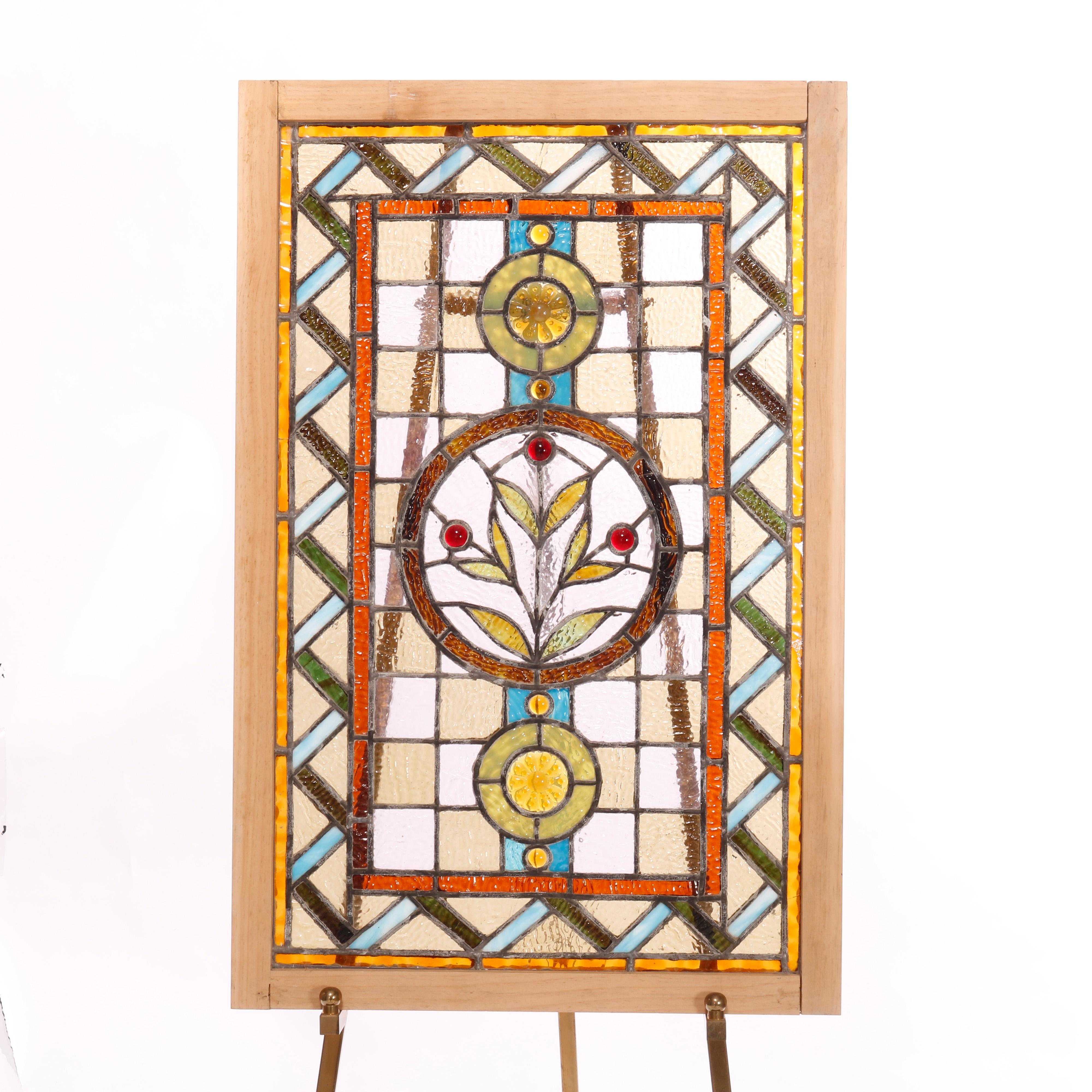 An antique pair of Arts & Crafts leaded and jeweled stained glass windows offer central stylized floral design with stylized ribbon bordering, seated in wood sashes, c1910

Measures - 35