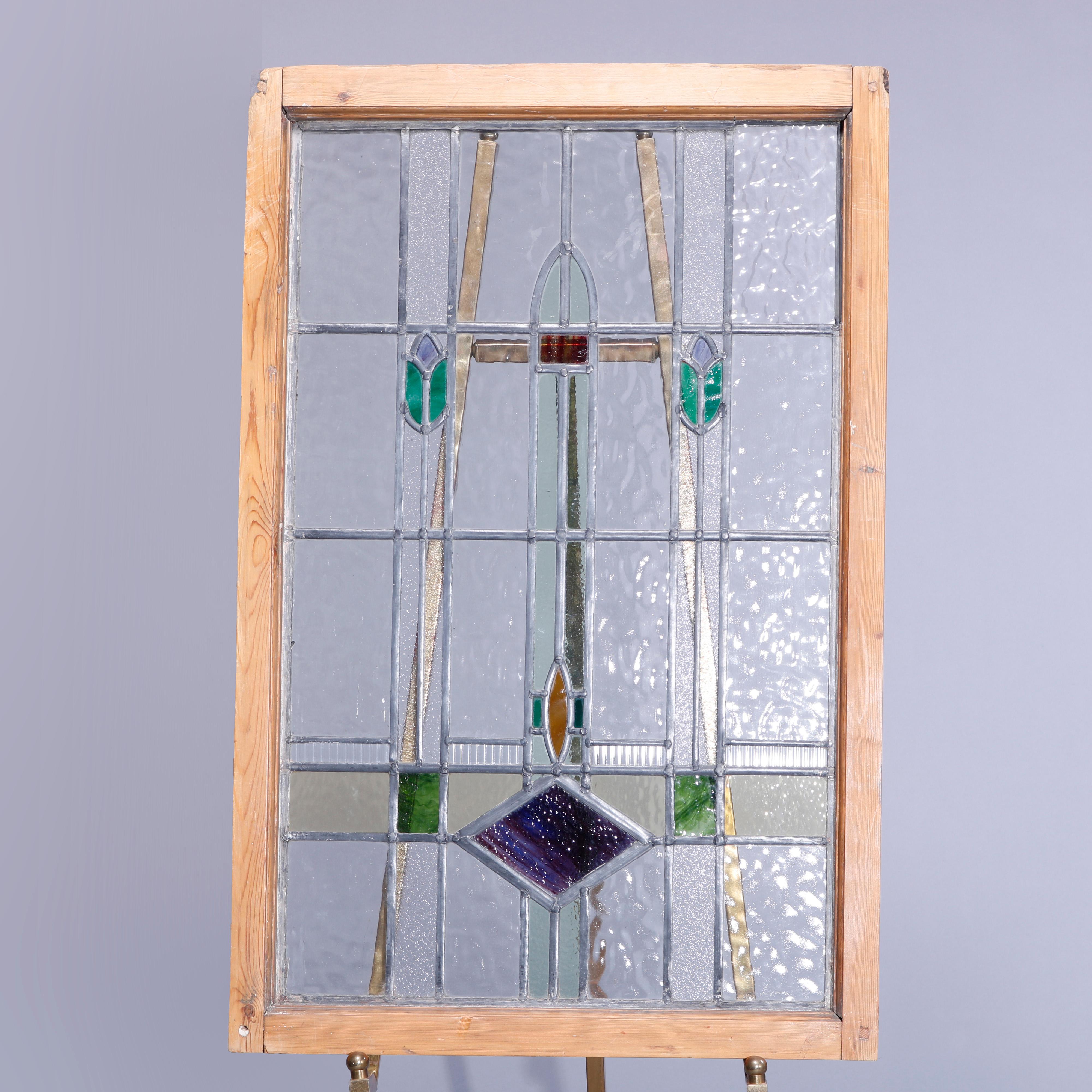 An antique Arts & Crafts leaded stained glass window panel offers geometric and stylized foliate elements seated in wood frame, c1915

Measures - 36.5''h x 23.75''w x 1.75''d.