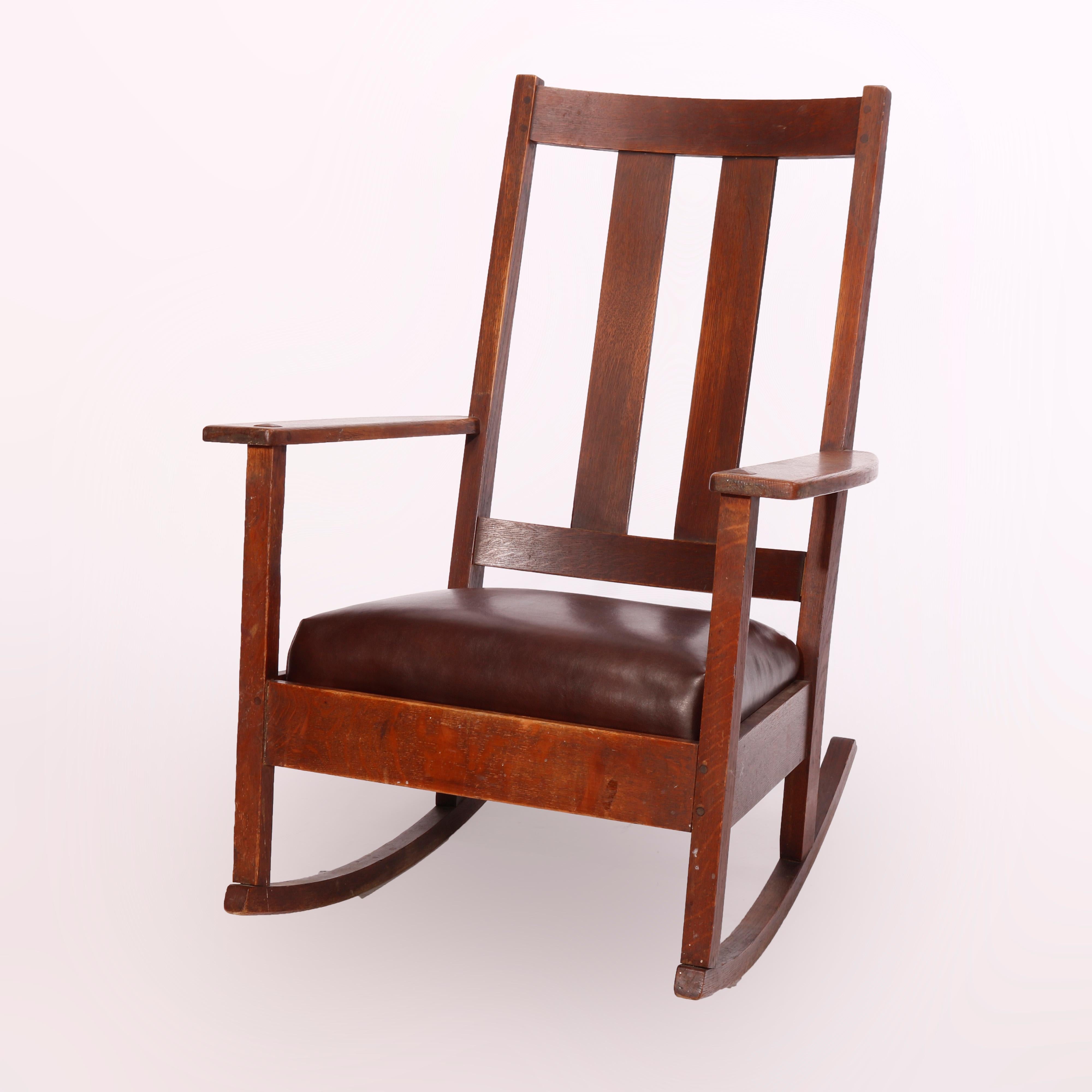 An antique Arts & Crafts rocking chair by Limbert offers oak construction with slat back and cushioned seat, signed Limbert, c1910

Measures - 37.75'' H x 27.75'' W x 33'' D; 14.5'' seat height.
