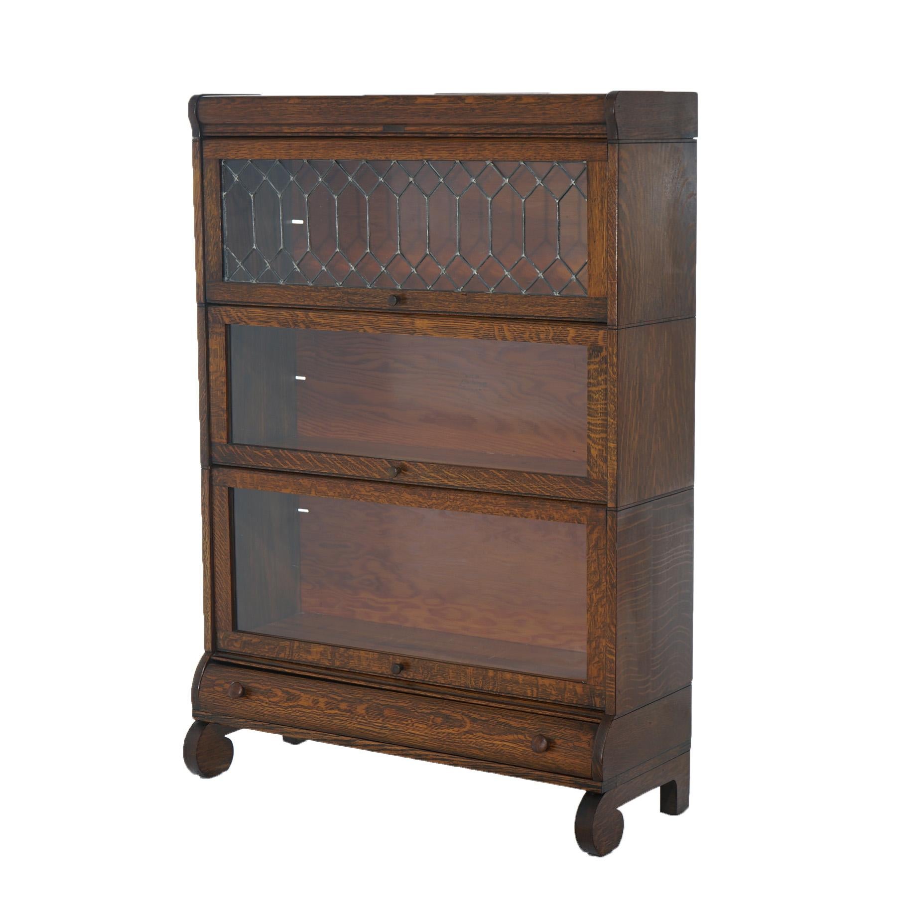 An antique Arts and Crafts Mission Lundstrom barrister bookcase offers quarter sawn oak construction with three stacks having pullout glass doors, one with leaded glass, lower drawer and raised on scroll form feet, c1910

Measures- 49''H x 33.75''W
