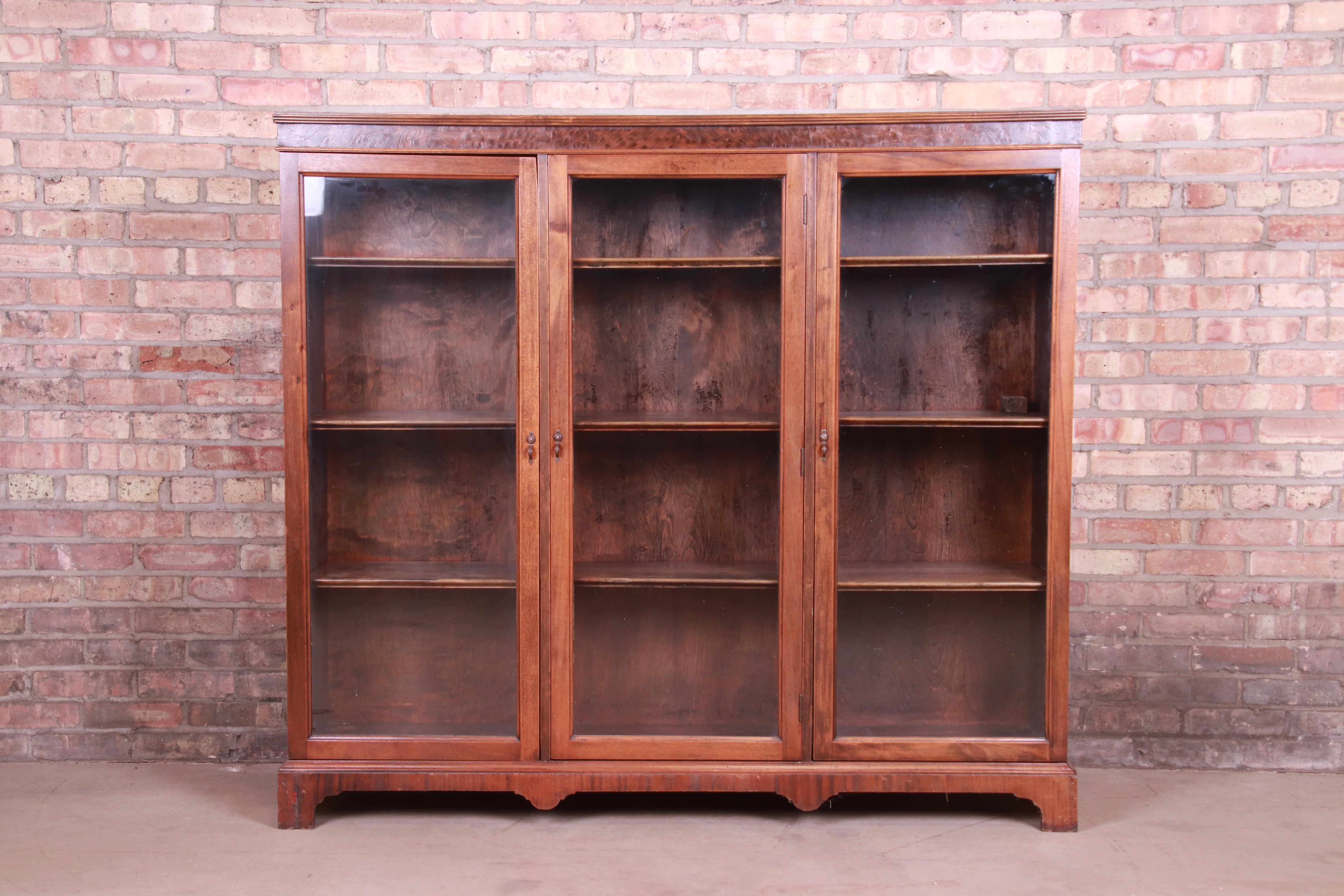 A gorgeous antique Arts & Crafts glass front triple bookcase

USA, circa 1900

Mahogany with burled walnut trim, and original glass doors and brass hardware.

Measures: 59